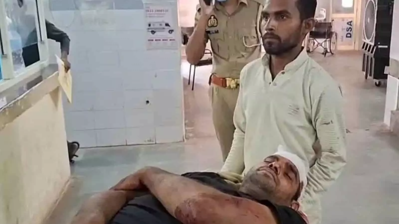 एटा के अस्पताल में स्ट्रेचर पर लेटा घायल व्यक्ति और पास खड़ा पुलिसकर्मी। एटा के अस्पताल में स्ट्रेचर पर लेटा घायल व्यक्ति और पास खड़ा पुलिसकर्मी।