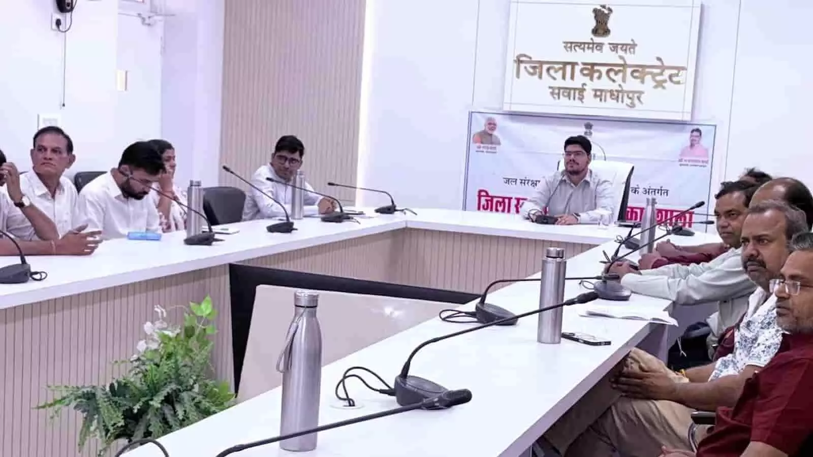 सवाई माधोपुर कलेक्ट्रेट सभागार में अधिकारियों की मौजूदगी में जल संरक्षण कार्यशाला के दौरान चेक सौंपते लोग।