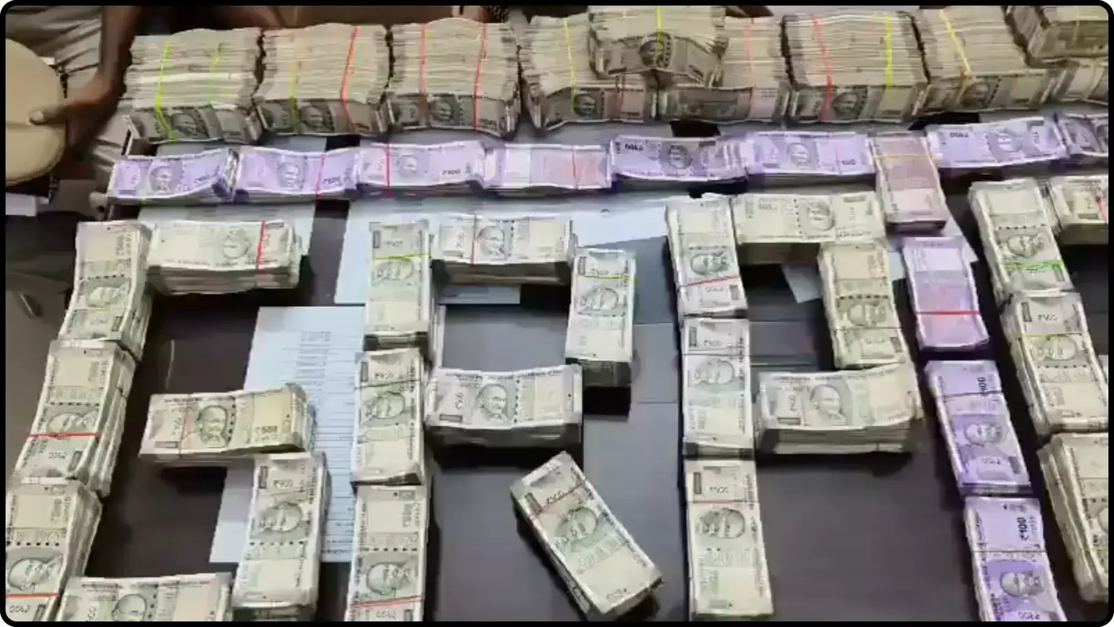 मेज पर व्यवस्थित तरीके से रखे गए पांच सौ और दो सौ रुपये के नोटों के बंडल।