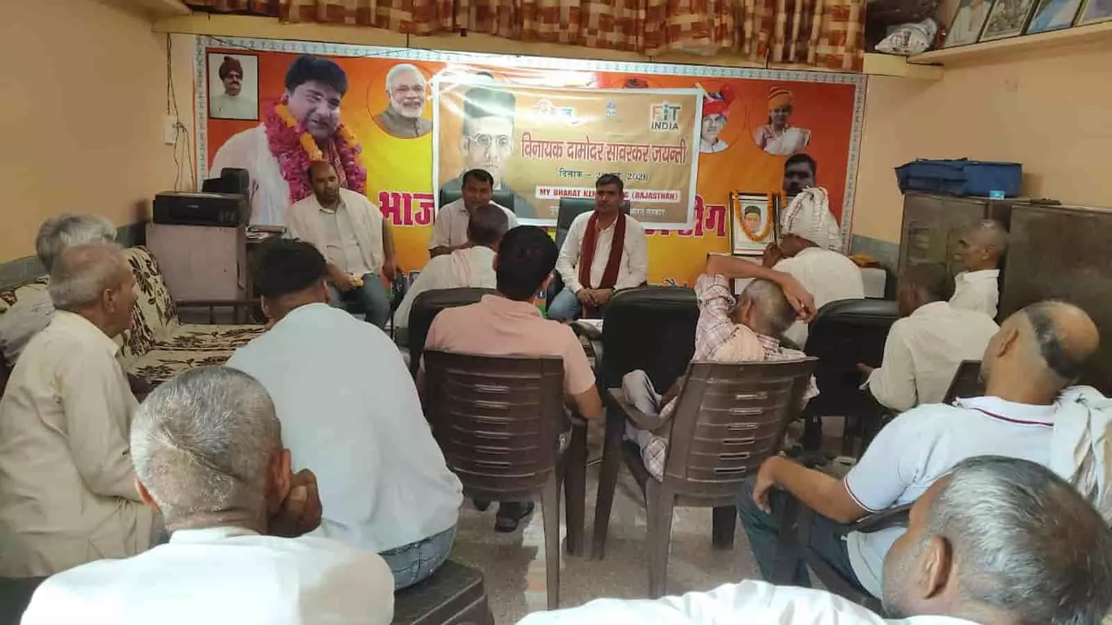 डीग के गिरसै मंडल कार्यालय में वीर सावरकर जयंती कार्यक्रम के दौरान मंच पर बैठे अतिथि और सामने उपस्थित ग्रामीण।