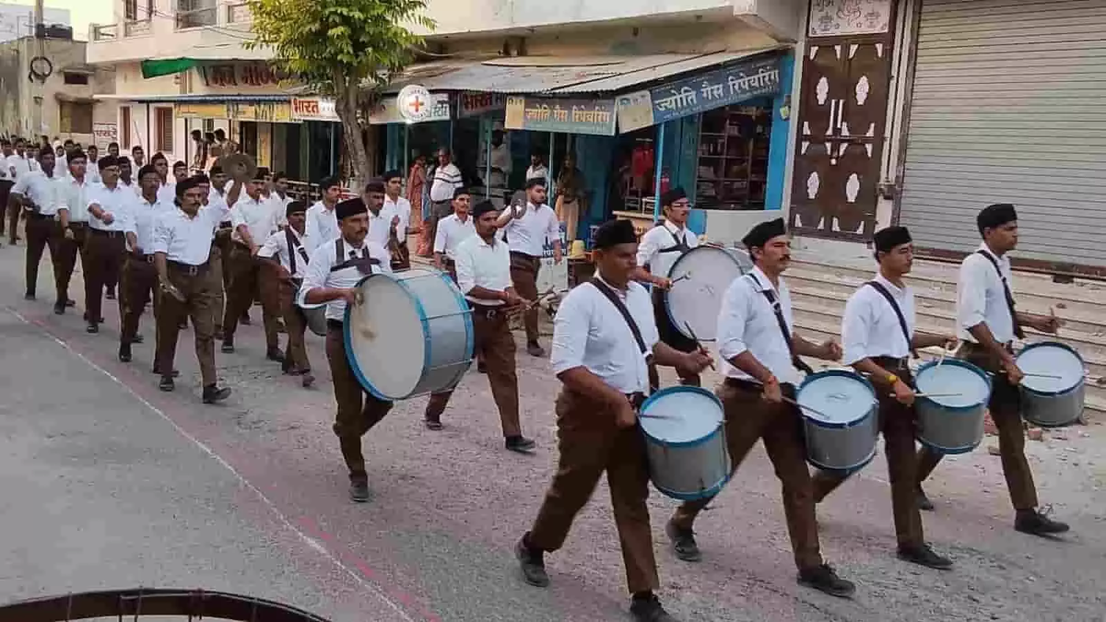 पूर्ण गणवेश में वाद्य यंत्र बजाते हुए राष्ट्रीय स्वयंसेवक संघ के स्वयंसेवक सड़क पर पथ संचलन करते हुए। पूर्ण गणवेश में वाद्य यंत्र बजाते हुए राष्ट्रीय स्वयंसेवक संघ के स्वयंसेवक सड़क पर पथ संचलन करते हुए।
