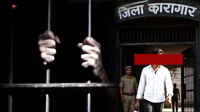 लोहे की सलाखों के पीछे बंधे हुए हाथ और दूसरी ओर जिला कारागार के मुख्य द्वार से बाहर आता हुआ एक व्यक्ति।