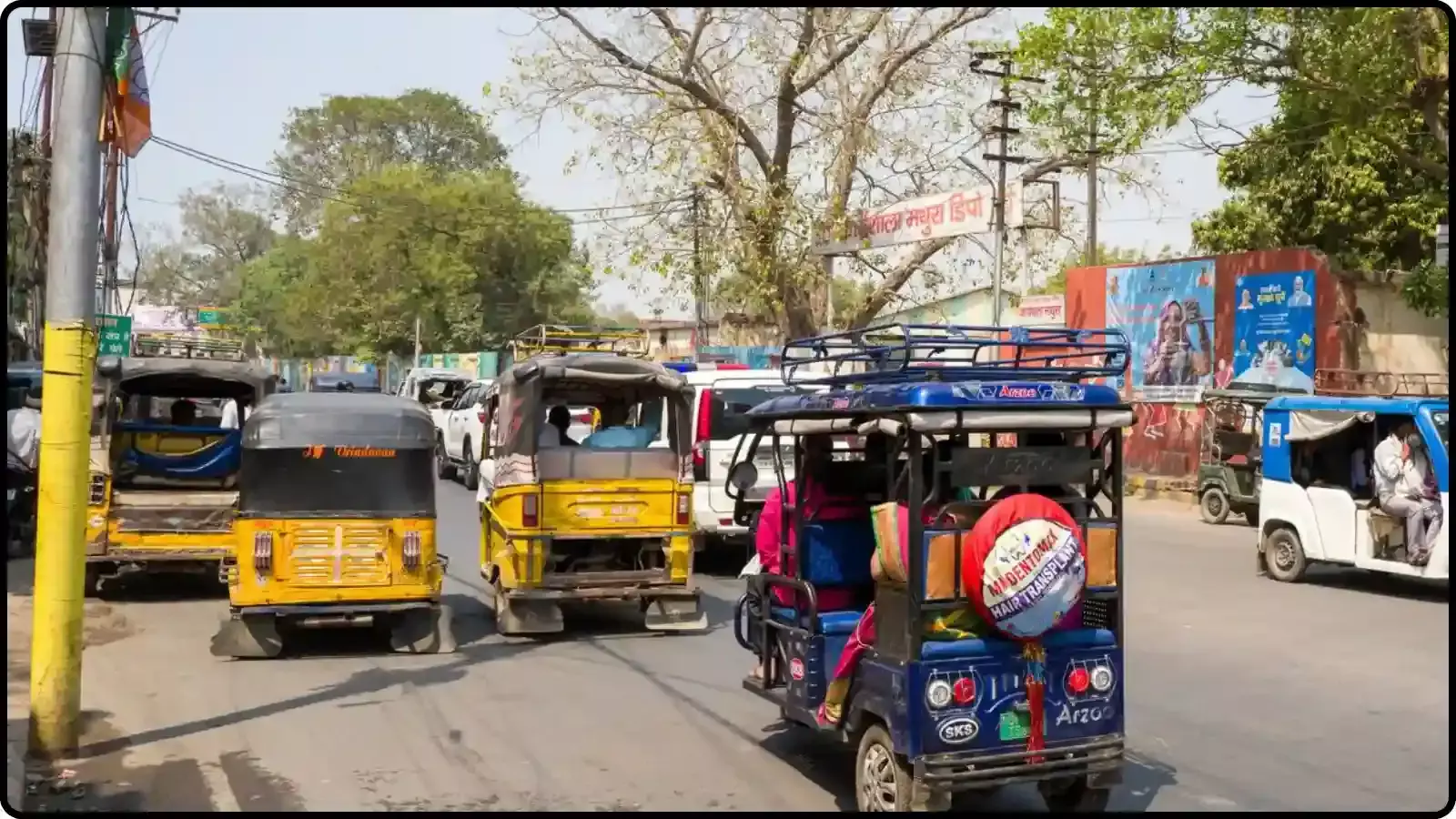 सड़क पर चलते हुए पीले और नीले रंग के ई-रिक्शा और ऑटोरिक्शा का एक दृश्य।