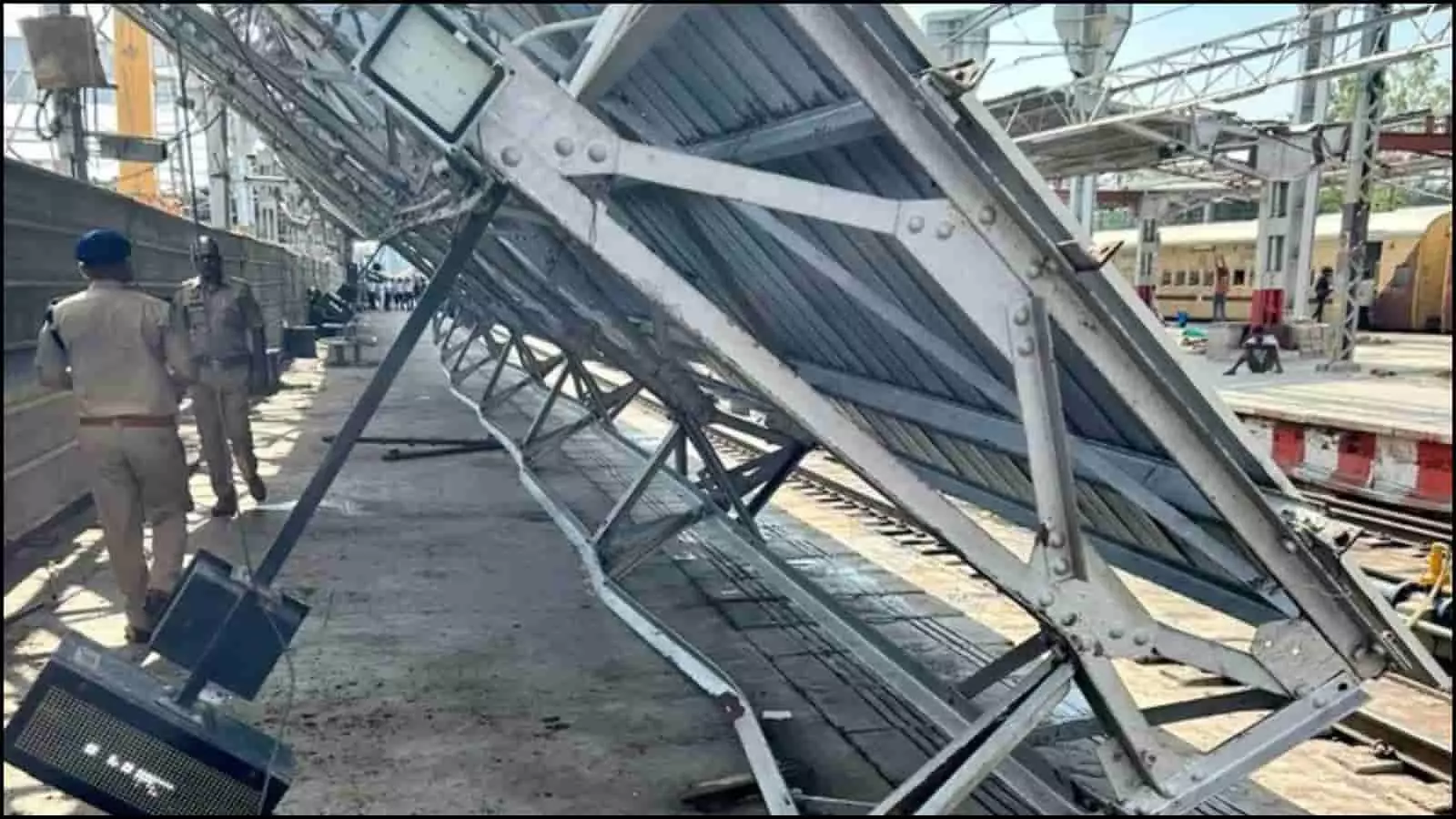 रेलवे प्लेटफार्म पर गिरा हुआ लोहे का टिन शेड और खड़े सुरक्षाकर्मी लखनऊ चारबाग रेलवे स्टेशन पर बुनियादी ढांचा ढहने के संदर्भ में।