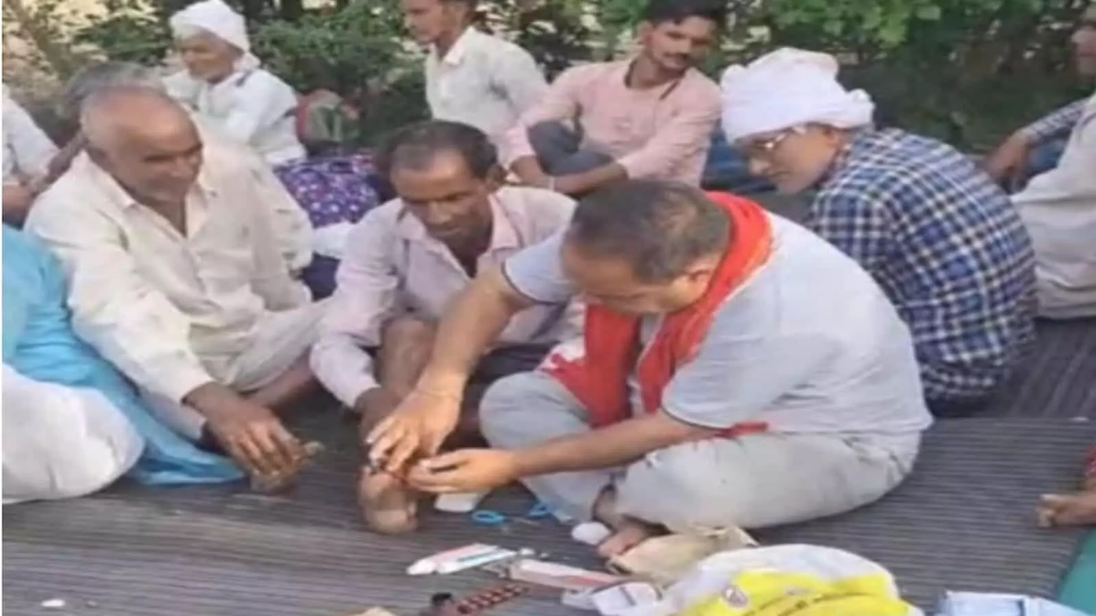 इच्छापूर्ण हनुमान मंदिर के पास जमीन पर बैठकर प्राथमिक चिकित्सा किट से परिक्रमार्थी के पैर का इलाज करते सेवादार। इच्छापूर्ण हनुमान मंदिर के पास जमीन पर बैठकर प्राथमिक चिकित्सा किट से परिक्रमार्थी के पैर का इलाज करते सेवादार।