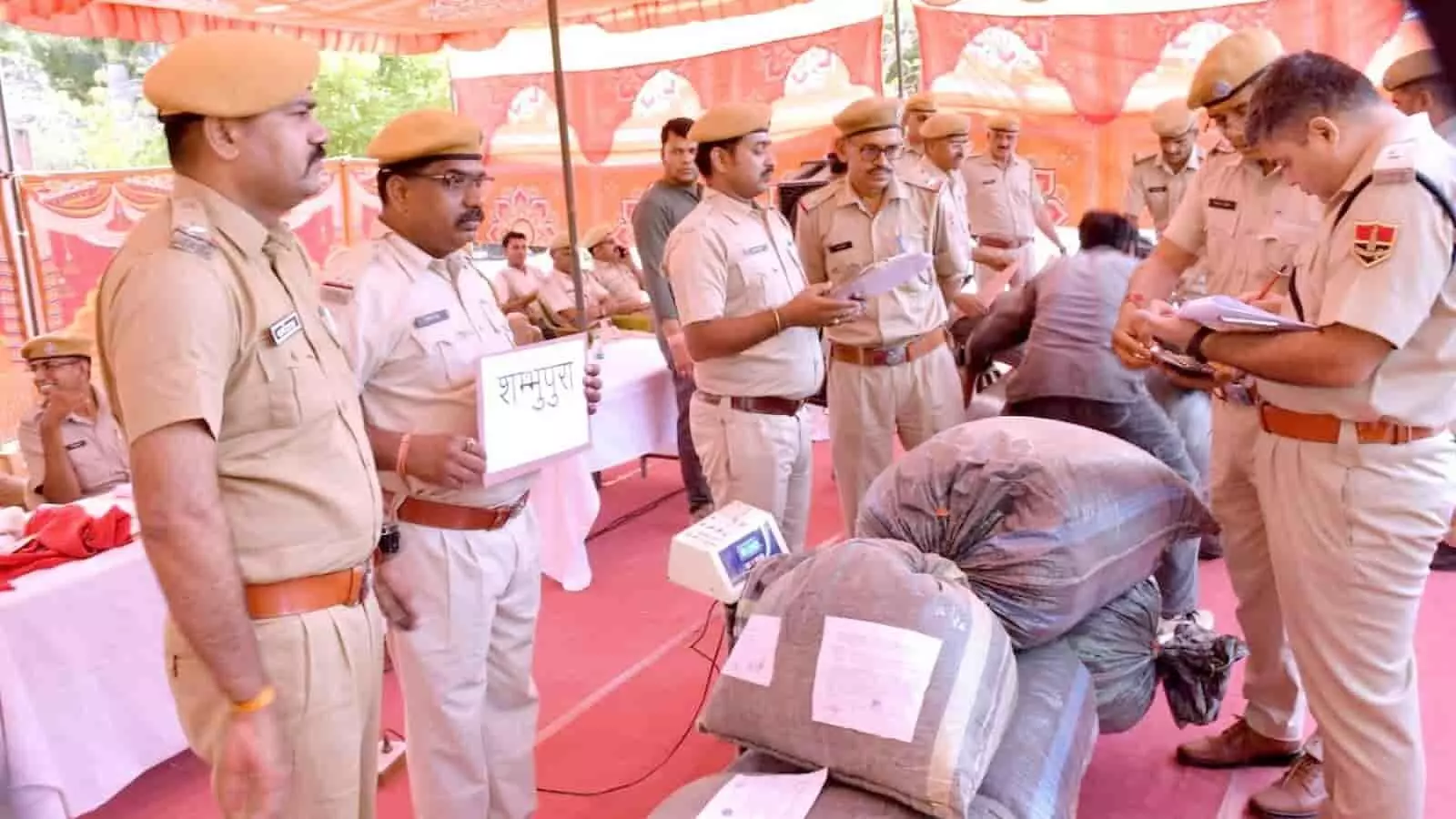 पंडाल के नीचे रखे मादक पदार्थों के कट्टों का वजन और रिकॉर्ड मिलान करते हुए पुलिस अधिकारी चित्तौड़गढ़ में जब्ती निस्तारण के दौरान