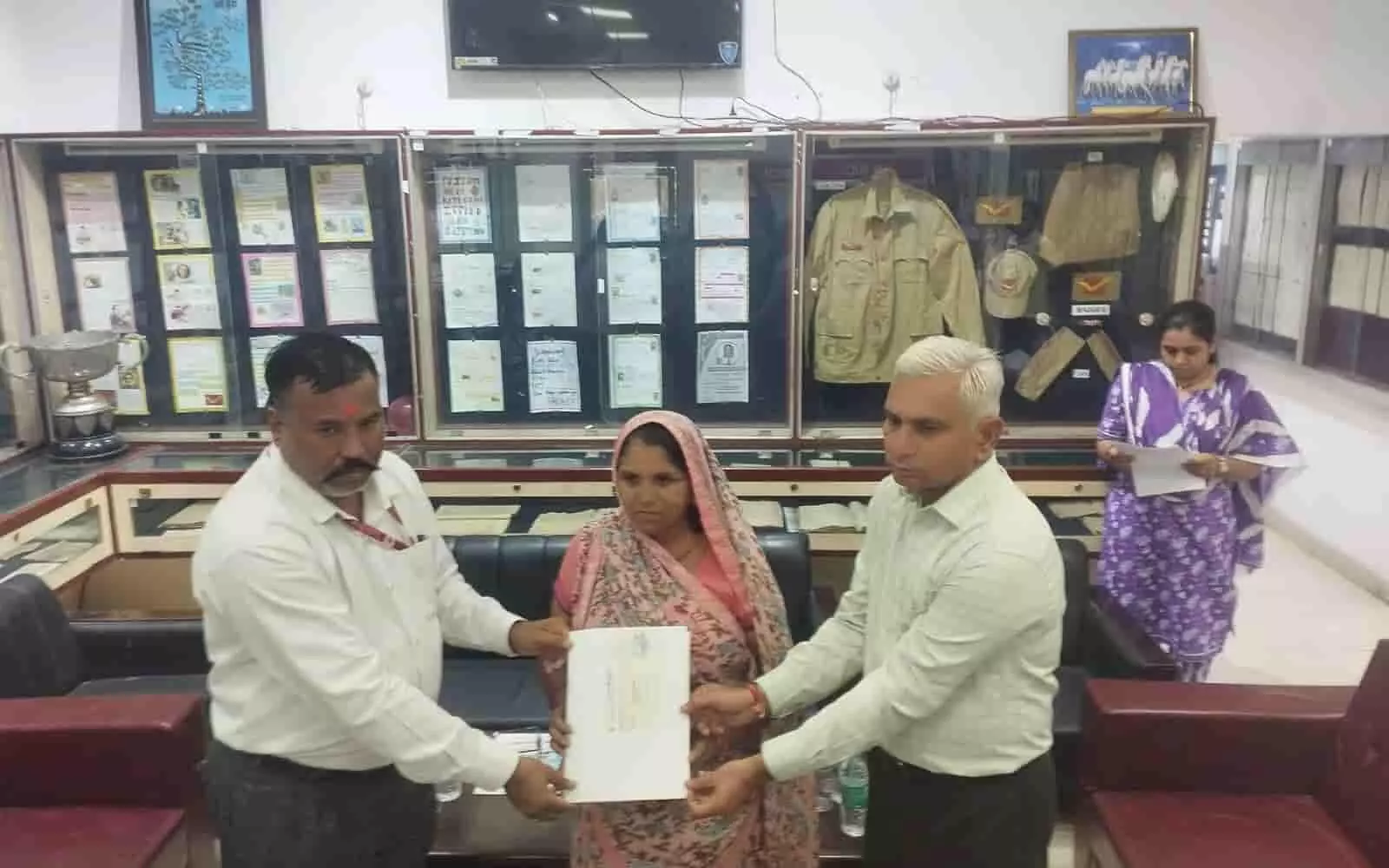 जयपुर में डाक जीवन बीमा का चेक प्राप्त करती मृतक की पत्नी और डाक अधिकारी। जयपुर में डाक जीवन बीमा का चेक प्राप्त करती मृतक की पत्नी और डाक अधिकारी।
