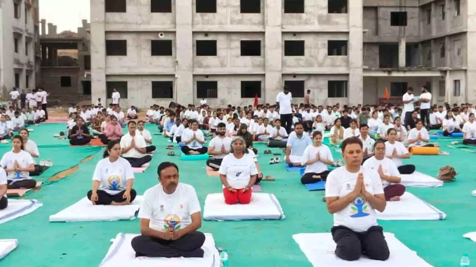 माधव विश्वविद्यालय सिरोही के खुले परिसर में चटाई पर बैठकर ध्यान मुद्रा में सामूहिक योगाभ्यास करते लोग।
