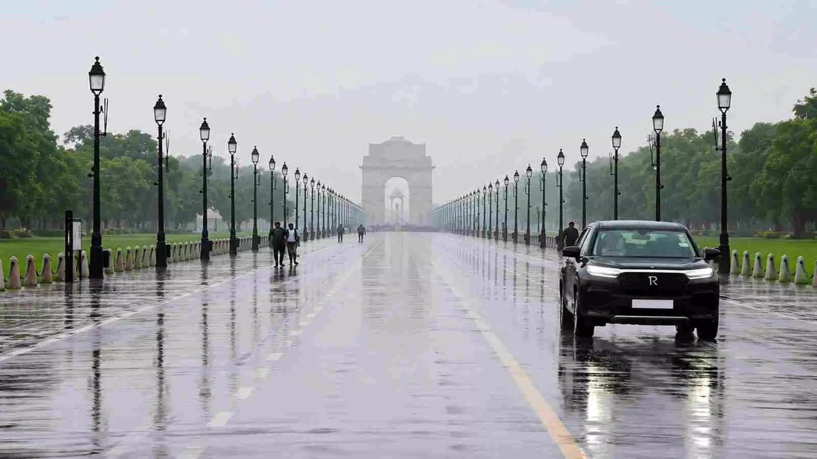 कर्तव्य पथ दिल्ली पर बारिश के दौरान चलती कार और दूर धुंध में दिखता इंडिया गेट। कर्तव्य पथ दिल्ली पर बारिश के दौरान चलती कार और दूर धुंध में दिखता इंडिया गेट।