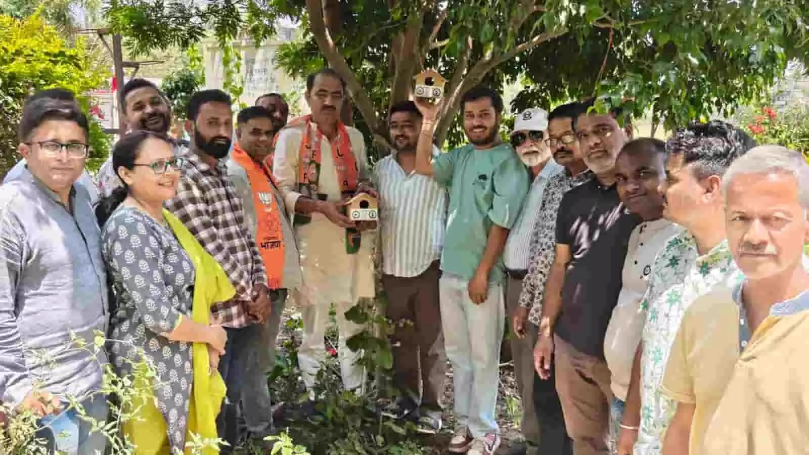 पेड़ पर पक्षियों के लिए परिंडे बांधते हुए भाजपा नेता और कार्यकर्ता आबू रोड में सामाजिक अभियान के दौरान उपस्थित हैं।