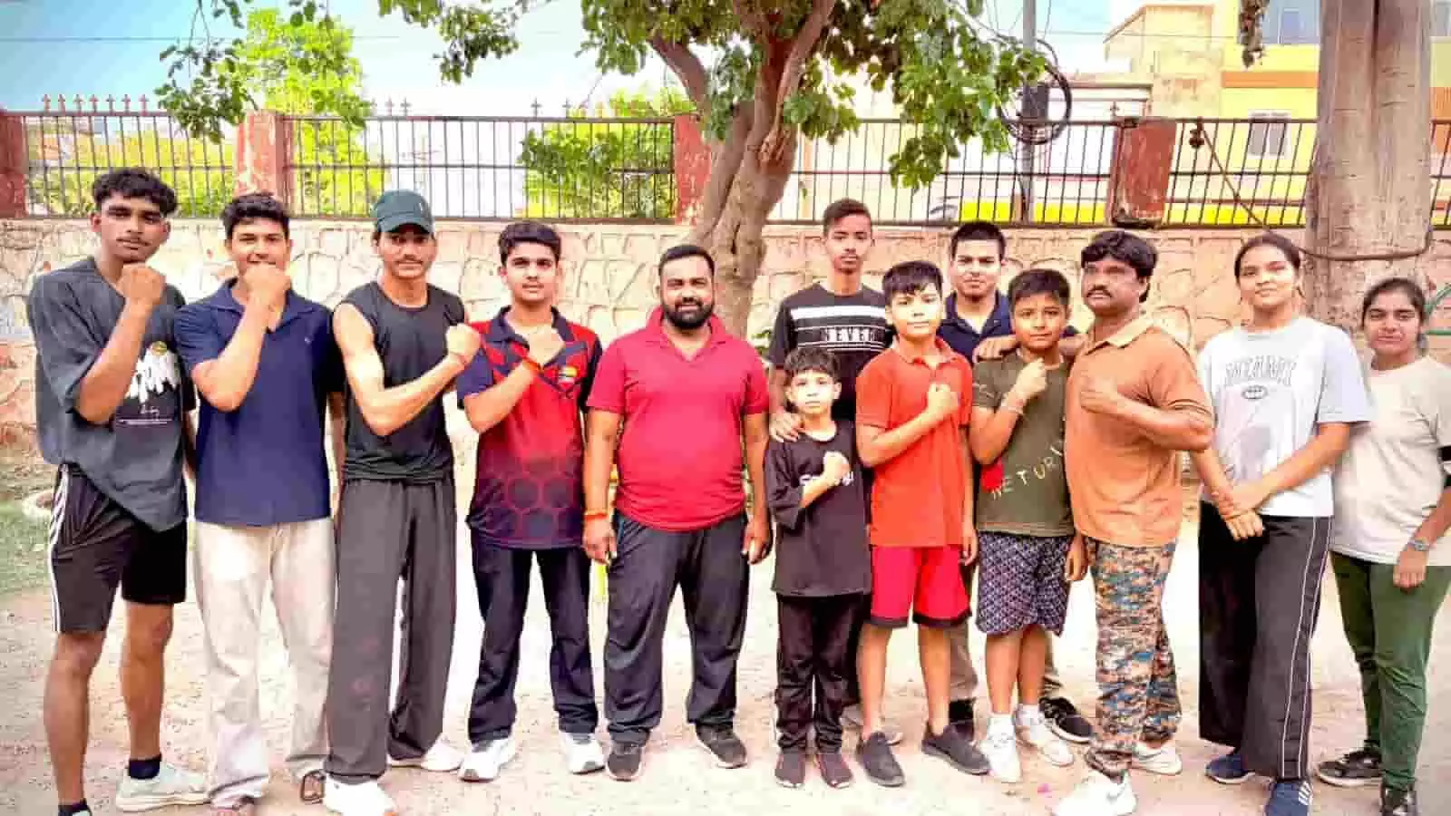करौली में राज्य स्तरीय मुक्केबाजी प्रतियोगिता के लिए रवाना होने से पहले पोज देते कतारबद्ध खिलाड़ी और कोच।