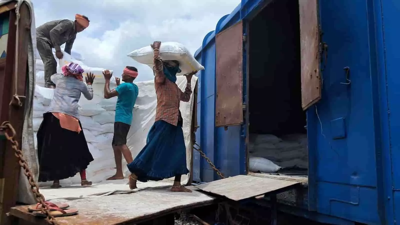 रेलवे यार्ड में खड़े मालगाड़ी के नीले वैगन में बोरे लोड करते श्रमिक माल लदान के संदर्भ में दिख रहे हैं। रेलवे यार्ड में खड़े मालगाड़ी के नीले वैगन में बोरे लोड करते श्रमिक माल लदान के संदर्भ में दिख रहे हैं।
