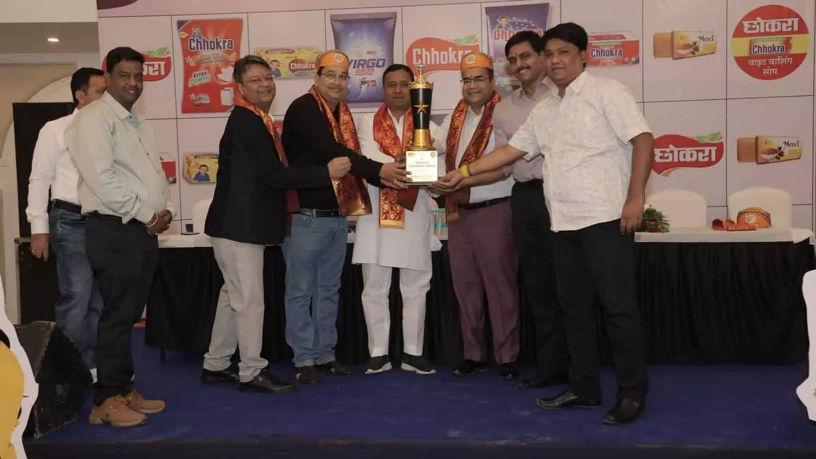 मंच पर उपस्थित अधिकारी और अतिथि विजेता व्यापारी को सम्मानित करते हुए।
