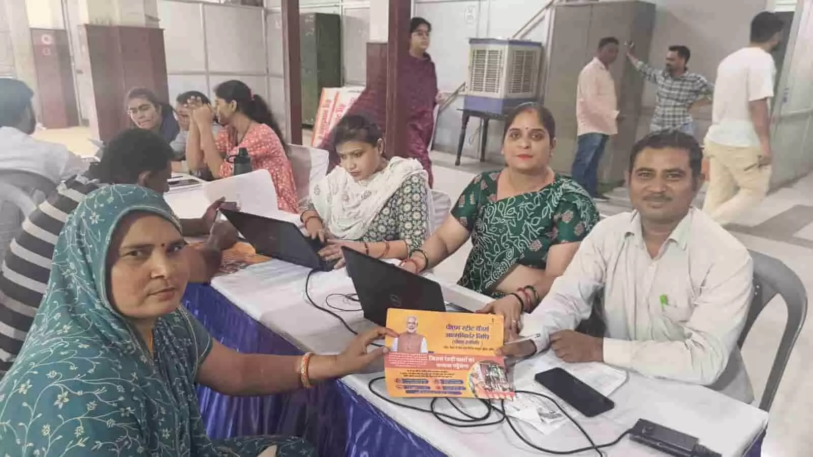 ऋण शिविर के काउंटर पर लैपटॉप के साथ बैठे बैंक कर्मी और आवेदन पत्र जमा करती महिला लाभार्थी। ऋण शिविर के काउंटर पर लैपटॉप के साथ बैठे बैंक कर्मी और आवेदन पत्र जमा करती महिला लाभार्थी।
