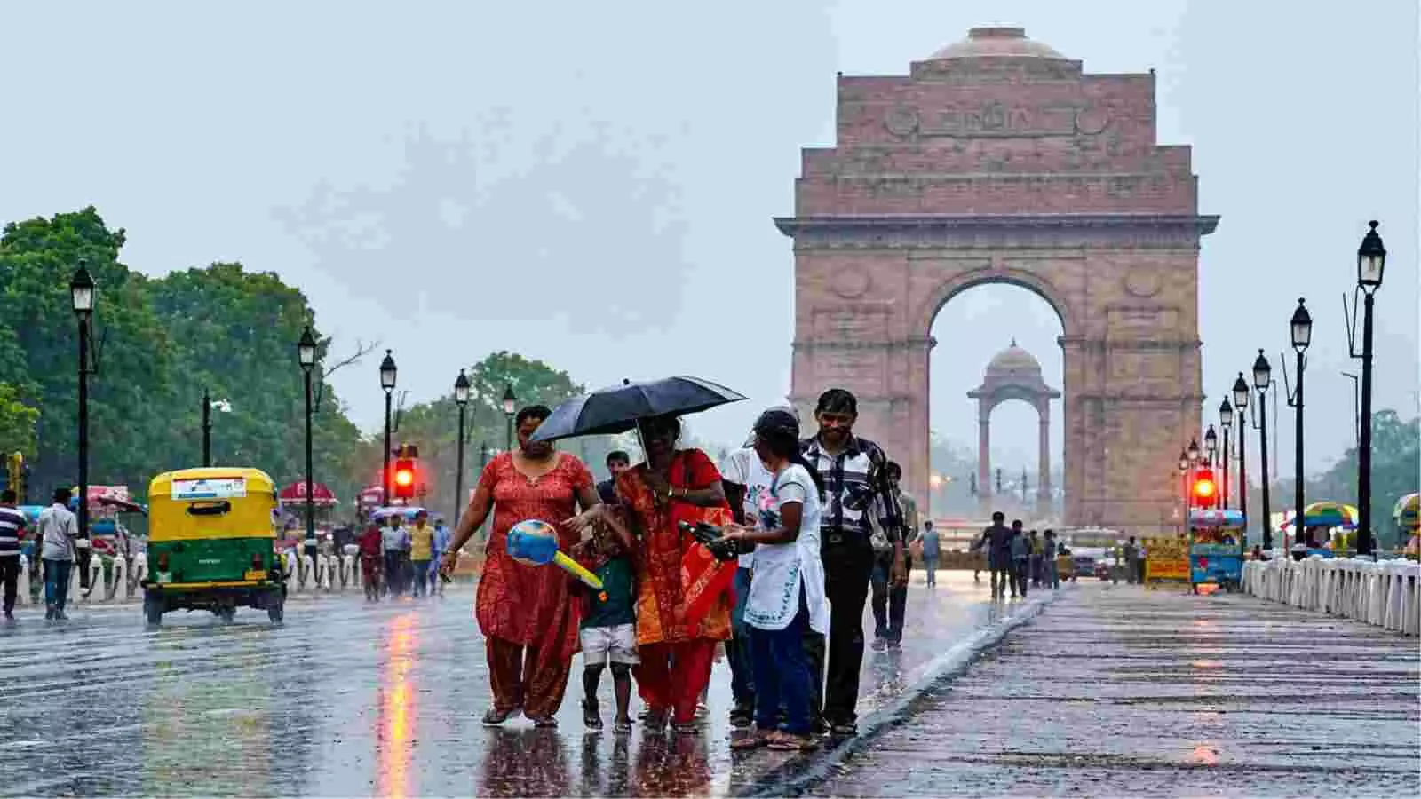 इंडिया गेट के सामने बारिश में छतरी लेकर चलते लोग और सड़क पर चलता ऑटो। इंडिया गेट के सामने बारिश में छतरी लेकर चलते लोग और सड़क पर चलता ऑटो।