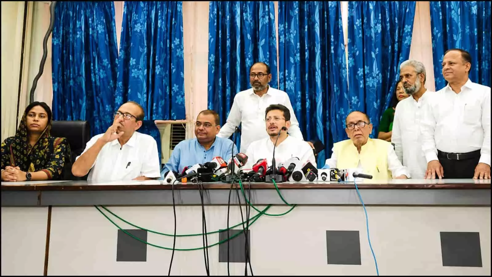 कार्यालय की मेज पर रखे माइक के सामने बैठकर बातचीत करते ऋतब्रता बनर्जी और अन्य नेता दिखाई दे रहे हैं।