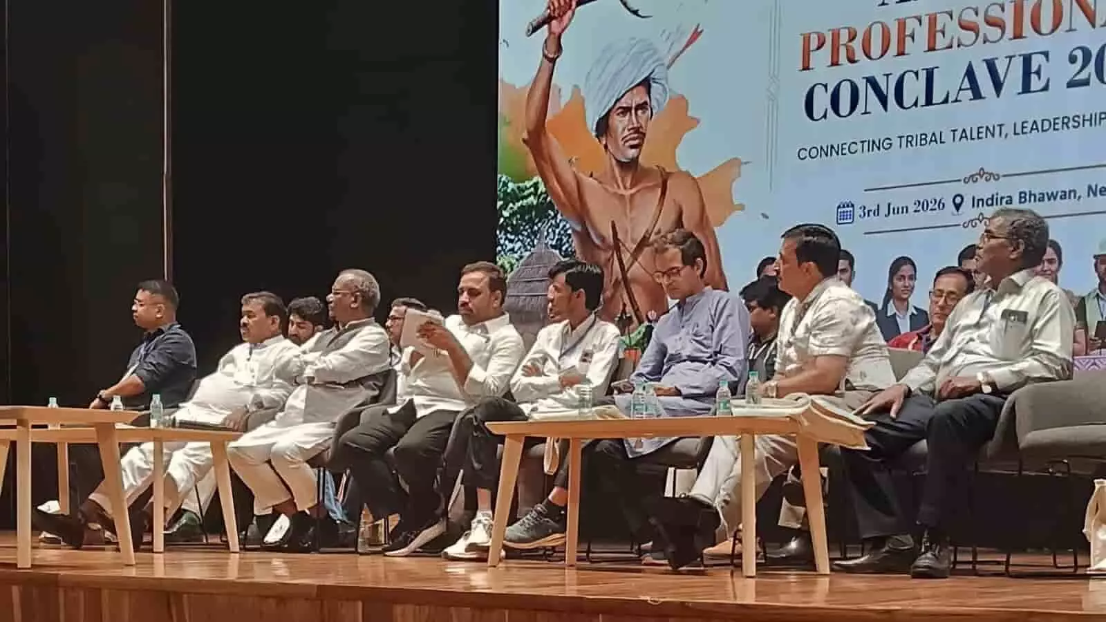 इंदिरा भवन नई दिल्ली के मंच पर कुर्सियों पर बैठे अतिथि और पीछे राष्ट्रीय आदिवासी प्रोफेशनल्स कॉन्क्लेव का बैनर।