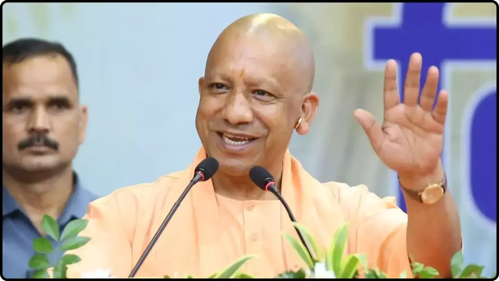मंच पर माइक के सामने हाथ उठाकर अभिवादन करते हुए मुख्यमंत्री योगी आदित्यनाथ उत्तर प्रदेश में एक जनसभा को संबोधित कर रहे हैं।