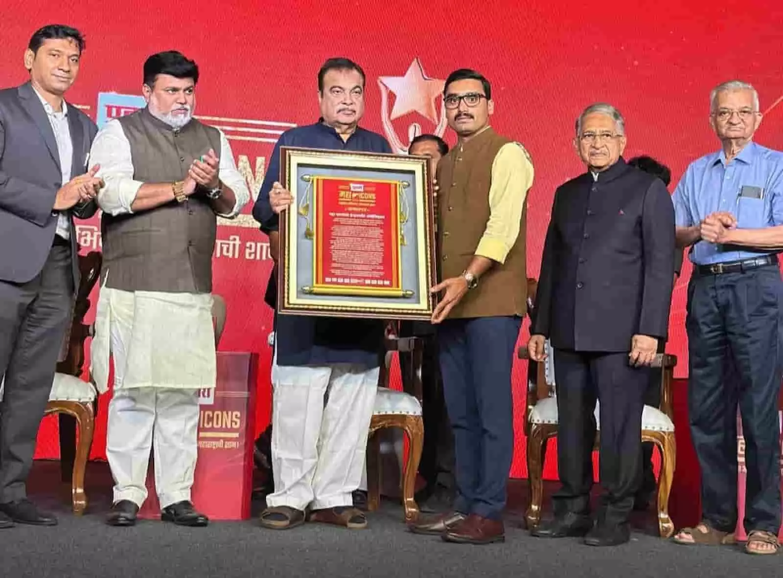 मुंबई में मंच पर पुढारी महा ICONS 2026 सम्मान पत्र हाथ में लिए खड़े डॉ. युवराज रामचंद्र येडूरे और नितिन गडकरी।