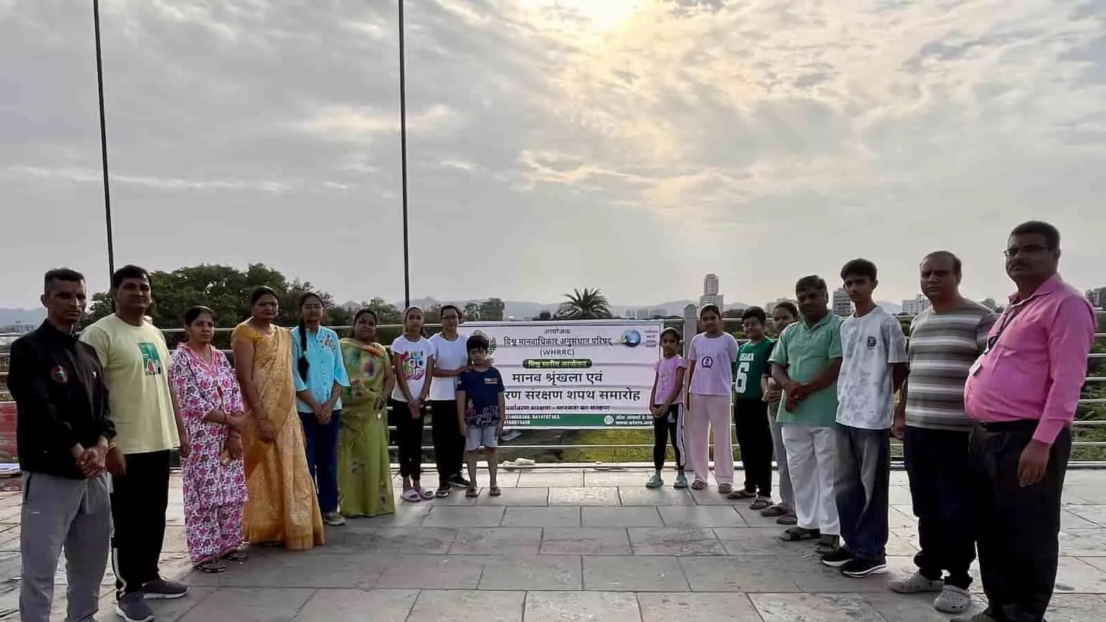 बैनर के सामने मानव श्रृंखला बनाकर खड़े लोग फतहनगर में पर्यावरण संरक्षण का संदेश दे रहे हैं।