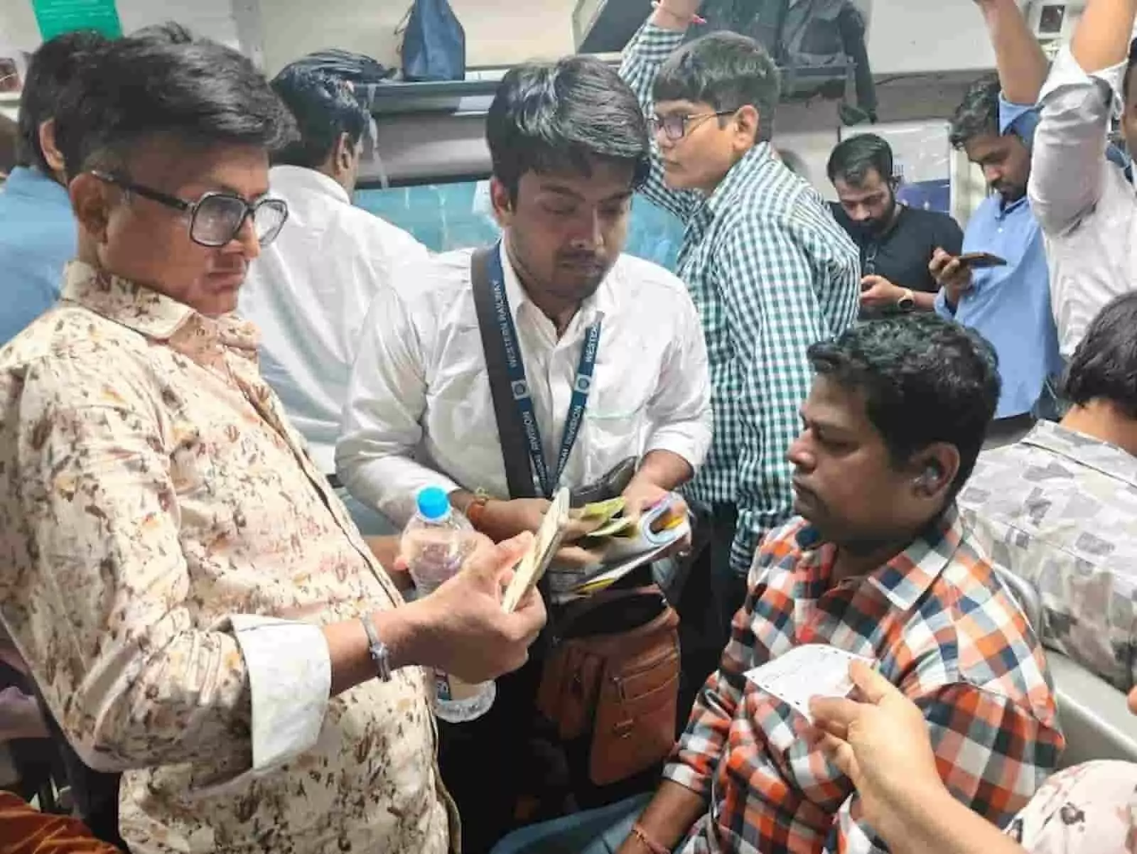 तस्वीर में रेल कर्मी मुंबई लोकल ट्रेन में यात्रियों के टिकटों की जांच कर रहे हैं।
