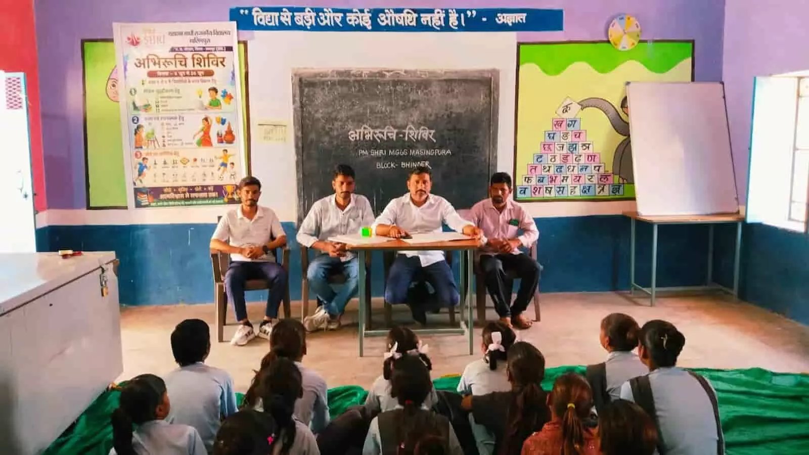 पीएम श्री एमजीजीएस मासिंगपुरा के कक्षा कक्ष में अभिरुचि शिविर के दौरान ब्लैकबोर्ड के सामने बैठे प्रभारी और छात्र पीएम श्री एमजीजीएस मासिंगपुरा के कक्षा कक्ष में अभिरुचि शिविर के दौरान ब्लैकबोर्ड के सामने बैठे प्रभारी और छात्र