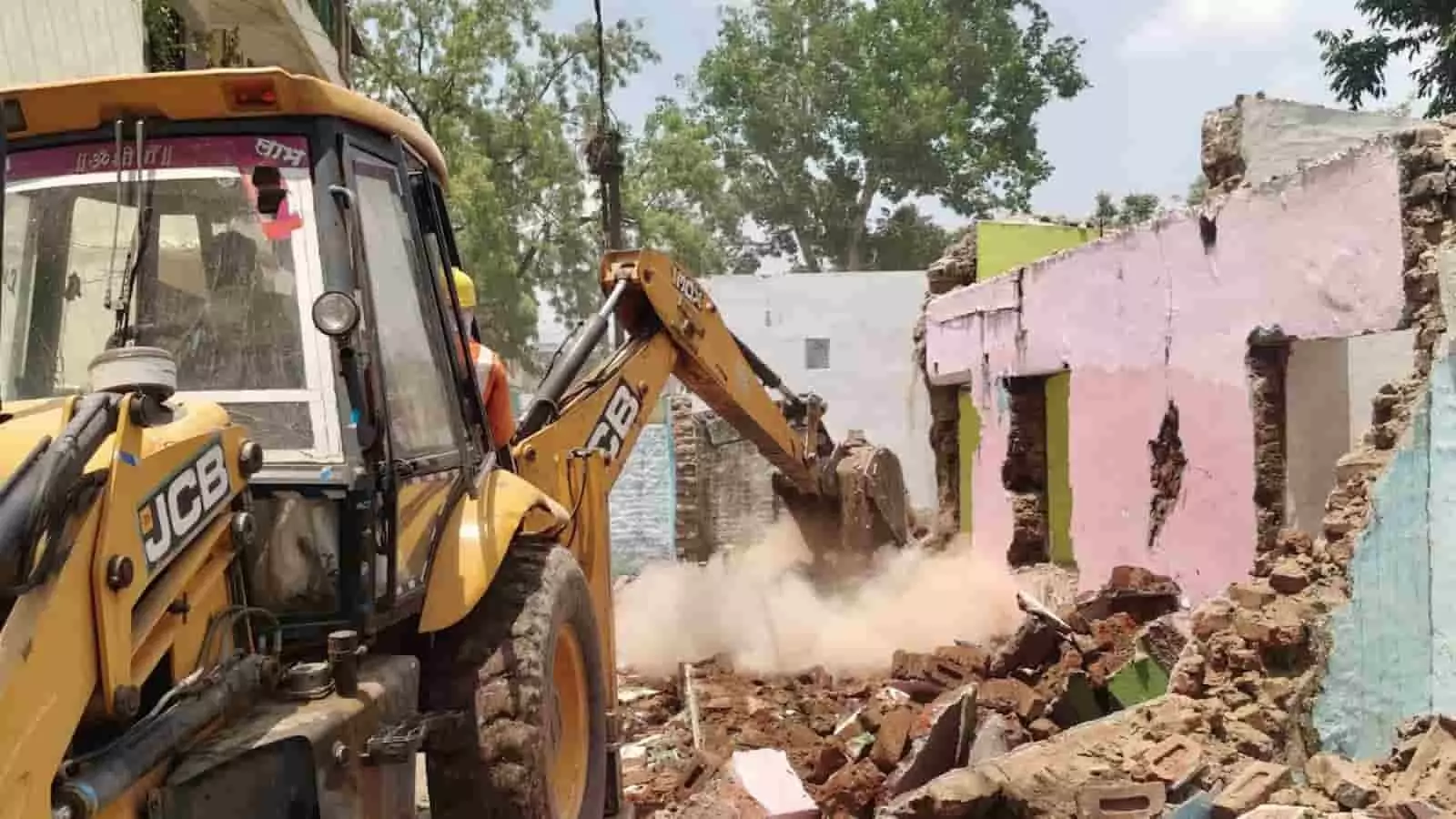 तस्वीर में नेपानगर में रेलवे लाइन विस्तार के लिए अवैध निर्माण हटाते हुए जेसीबी मशीन दिख रही है।