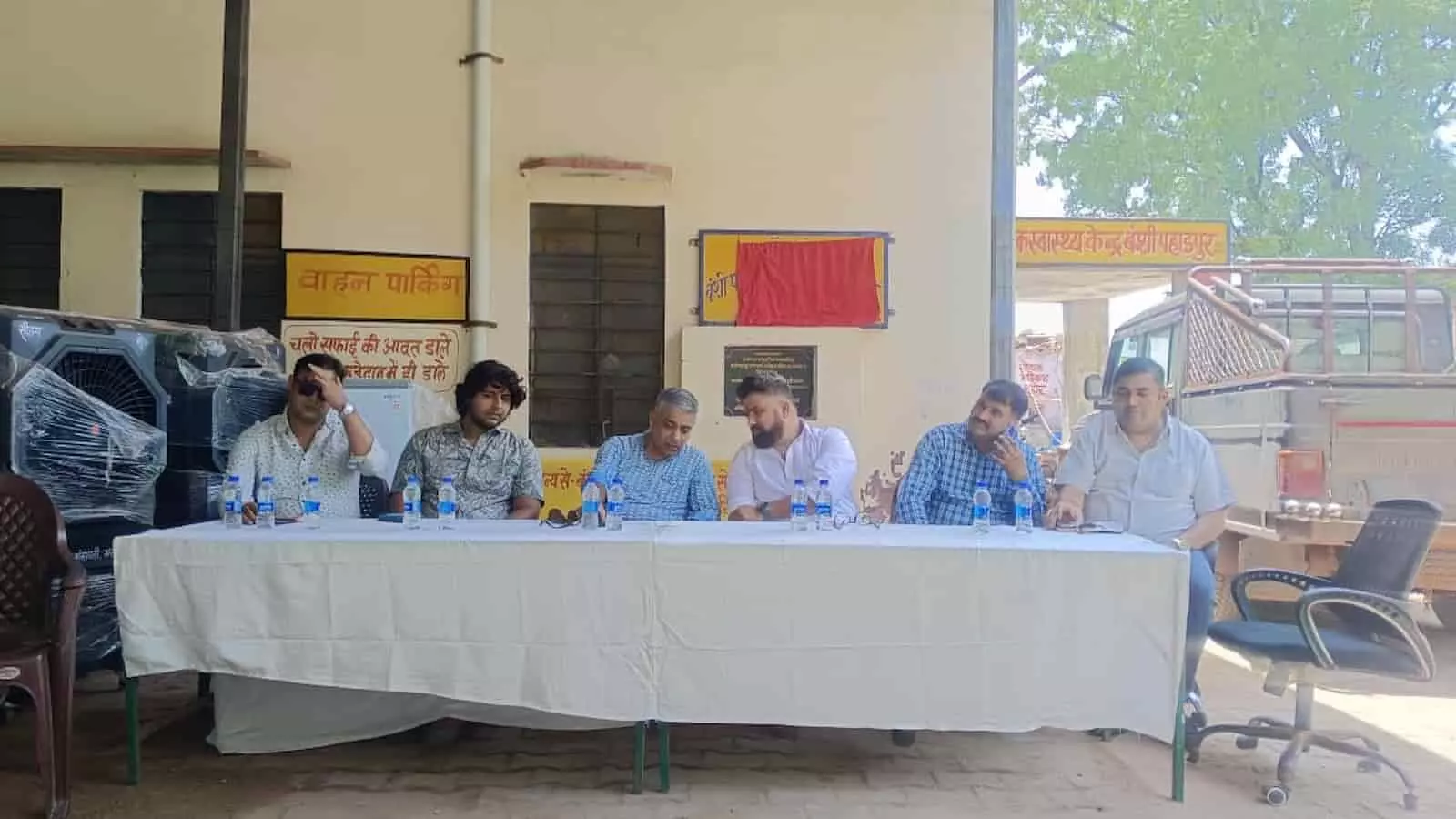 बंसी पहाड़पुर सामुदायिक स्वास्थ्य केंद्र में मेज के पीछे बैठे अधिकारी और दान की गई सामग्री।
