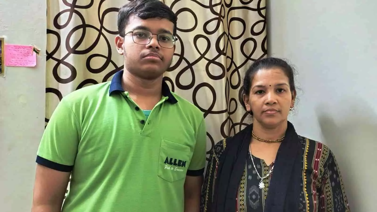 कमरे के अंदर पर्दे के सामने खड़े चश्मा पहने हुए एक युवक और उसकी माता की फाइल फोटो। कमरे के अंदर पर्दे के सामने खड़े चश्मा पहने हुए एक युवक और उसकी माता की फाइल फोटो।