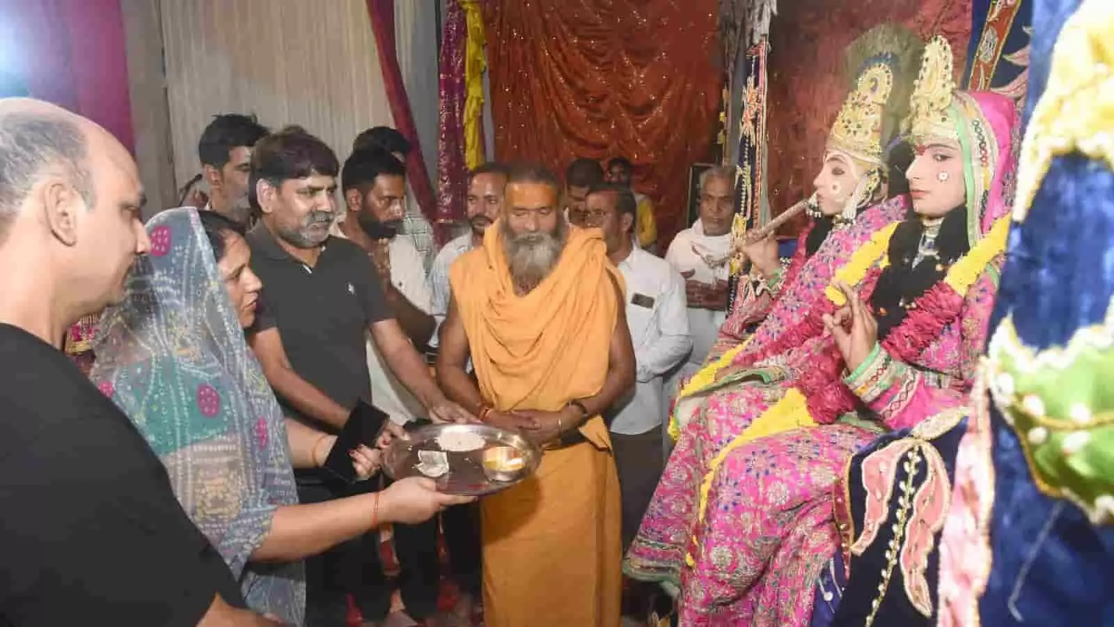 हनुमान टेकरी आश्रम भीलवाड़ा में धार्मिक आयोजन के दौरान श्रीकृष्ण-राधा बने कलाकारों के साथ खड़े महंत और श्रद्धालु। हनुमान टेकरी आश्रम भीलवाड़ा में धार्मिक आयोजन के दौरान श्रीकृष्ण-राधा बने कलाकारों के साथ खड़े महंत और श्रद्धालु।