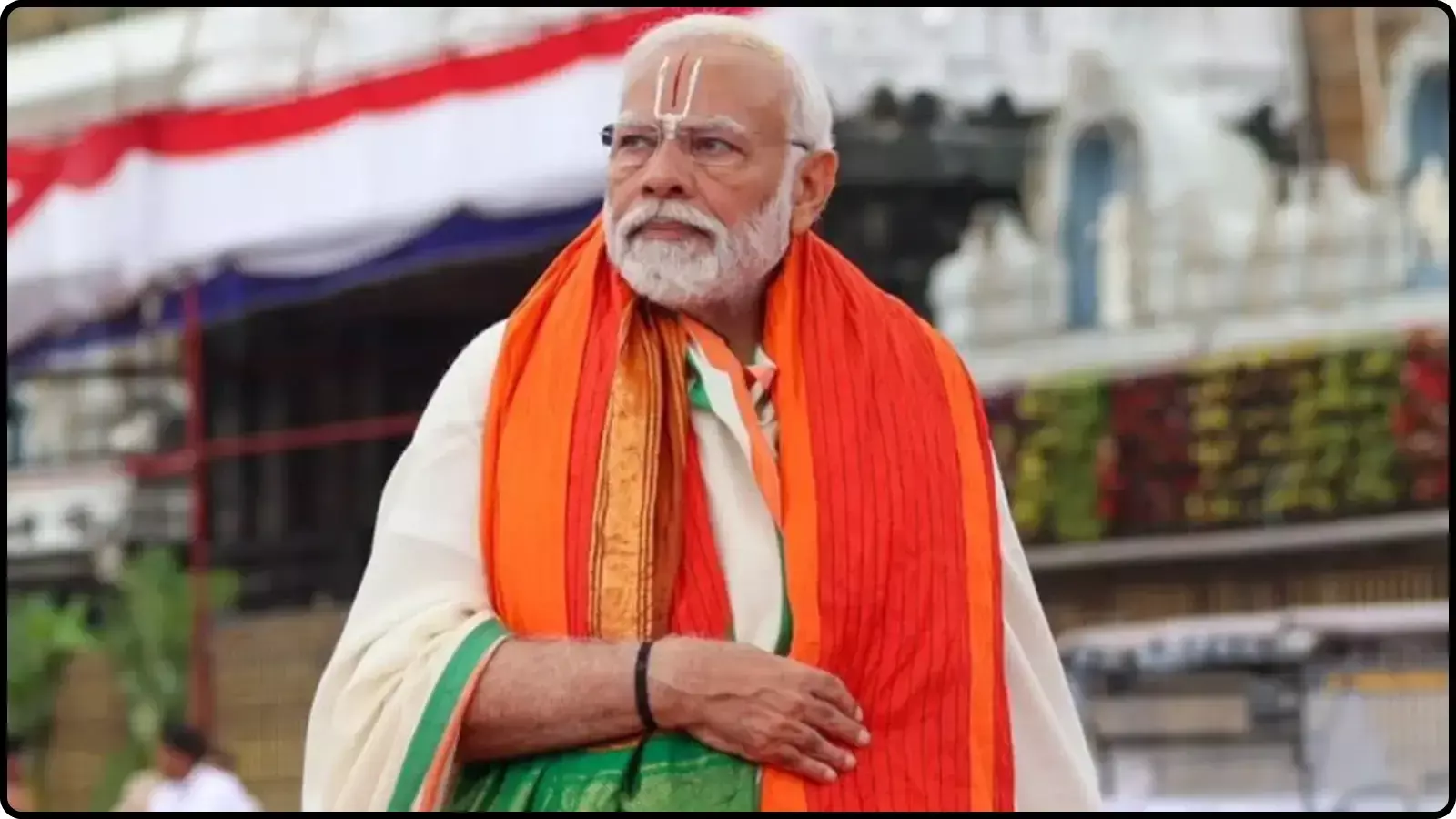 पारंपरिक वस्त्रों और तिलक में प्रधानमंत्री नरेंद्र मोदी एक धार्मिक स्थल परिसर के बाहर खड़े हैं। पारंपरिक वस्त्रों और तिलक में प्रधानमंत्री नरेंद्र मोदी एक धार्मिक स्थल परिसर के बाहर खड़े हैं।