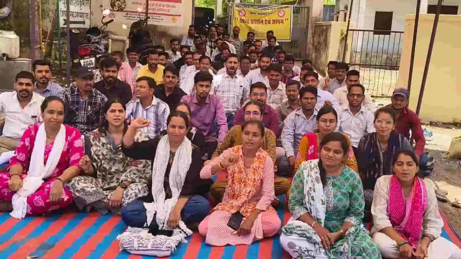 कार्यालय परिसर में दरी पर बैठकर राज्य सरकार के खिलाफ प्रदर्शन करते हुए कृषि विभाग के पुरुष और महिला कर्मचारी। कार्यालय परिसर में दरी पर बैठकर राज्य सरकार के खिलाफ प्रदर्शन करते हुए कृषि विभाग के पुरुष और महिला कर्मचारी।