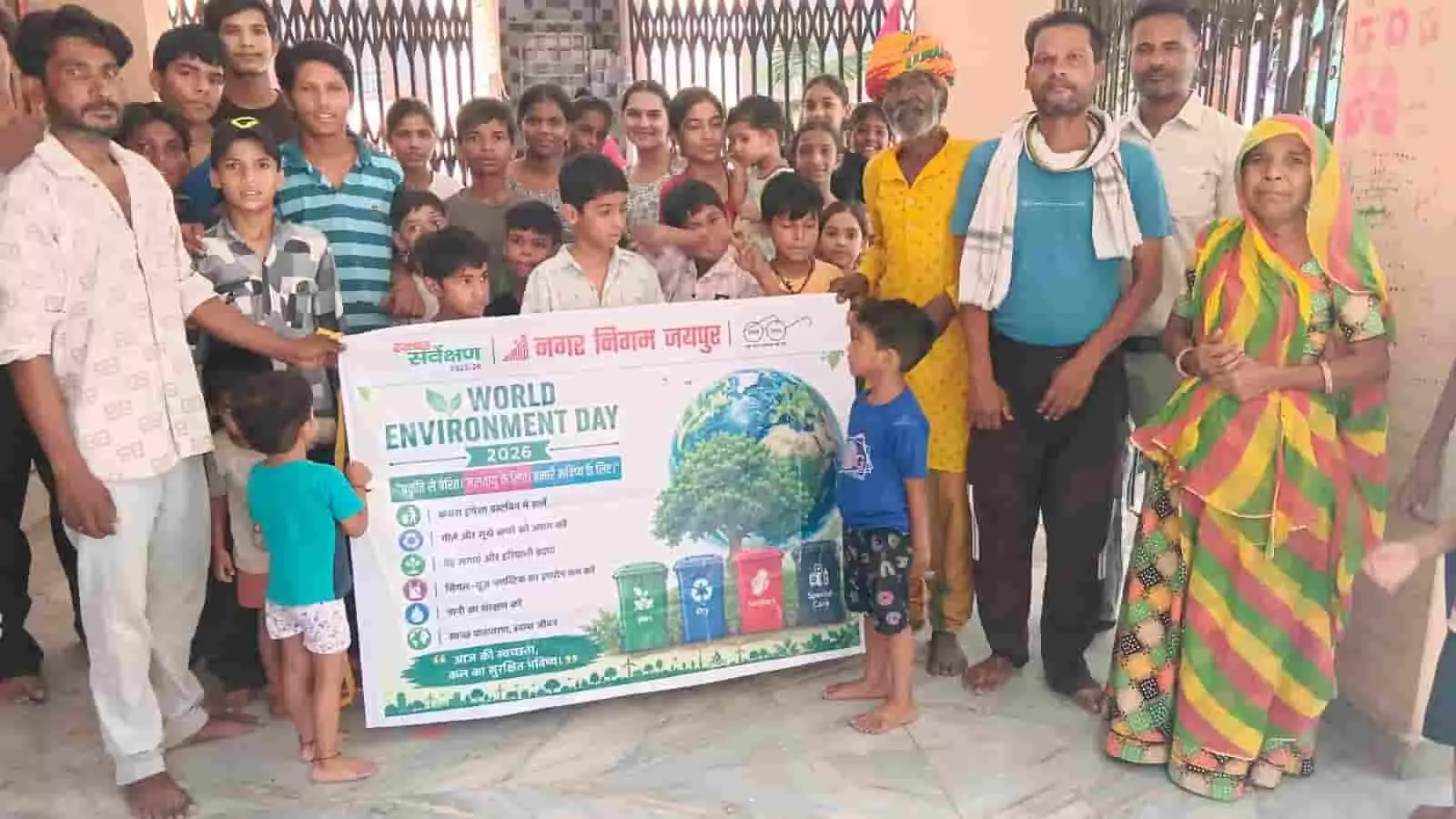जयपुर के दयानंद पुरी में विश्व पर्यावरण दिवस के बैनर के साथ खड़े स्थानीय लोग और बच्चे। जयपुर के दयानंद पुरी में विश्व पर्यावरण दिवस के बैनर के साथ खड़े स्थानीय लोग और बच्चे।