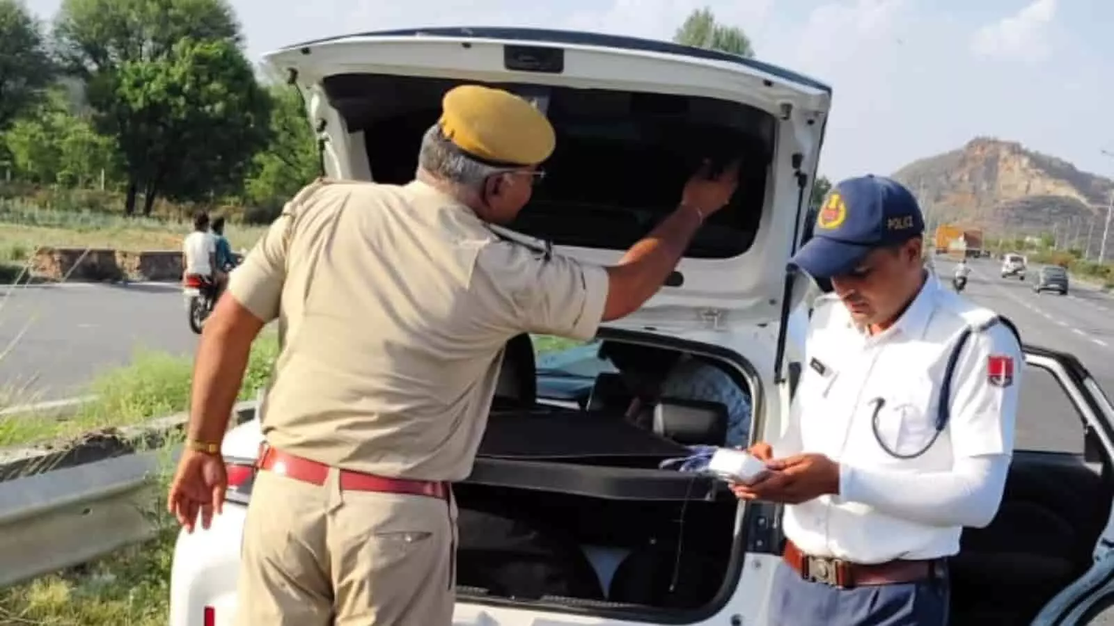 हाईवे पर खड़ी सफेद कार की डिग्गी खोलकर जांच करते राजस्थान पुलिस के जवान हाईवे पर खड़ी सफेद कार की डिग्गी खोलकर जांच करते राजस्थान पुलिस के जवान