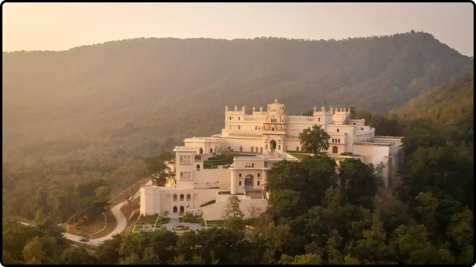 पहाड़ियों और पेड़ों के बीच बना एक सफेद ऐतिहासिक महल खजुराहो में ओबेरॉय राजगढ़ पैलेस के संदर्भ में। पहाड़ियों और पेड़ों के बीच बना एक सफेद ऐतिहासिक महल खजुराहो में ओबेरॉय राजगढ़ पैलेस के संदर्भ में।