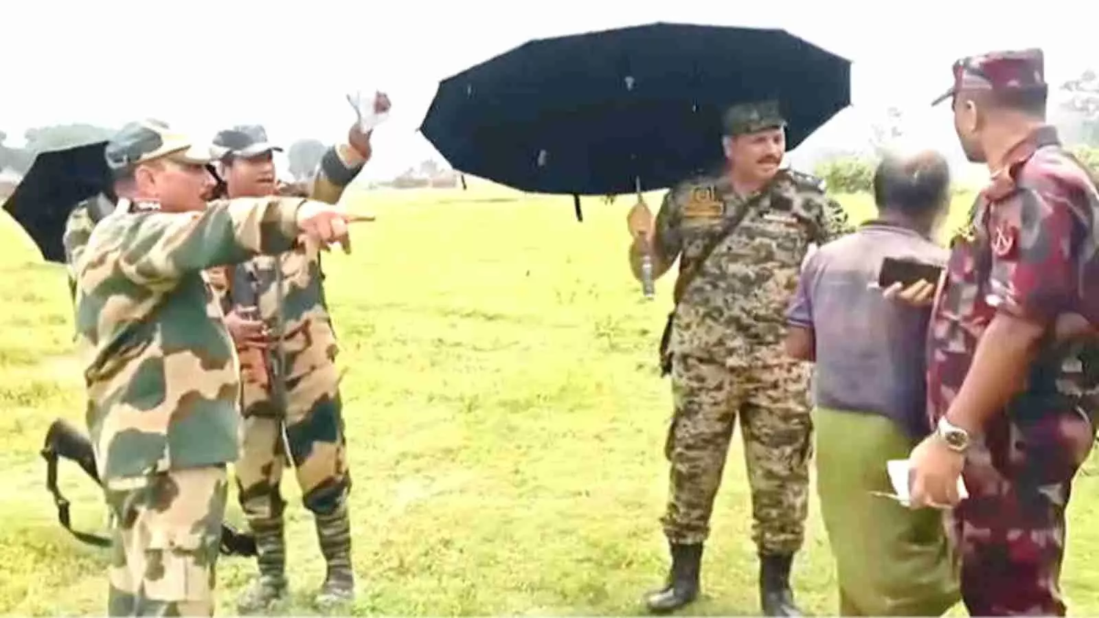 सैन्य वर्दी में सुरक्षा बल के जवान और अधिकारी खुली जमीन पर छाता लिए आपस में बातचीत करते हुए। सैन्य वर्दी में सुरक्षा बल के जवान और अधिकारी खुली जमीन पर छाता लिए आपस में बातचीत करते हुए।