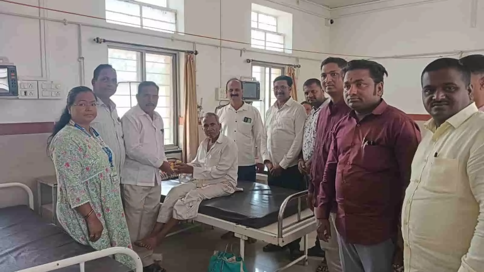तस्वीर में कुछ लोग अस्पताल के बेड पर बैठे एक बुजुर्ग मरीज को फल देते हुए। तस्वीर में कुछ लोग अस्पताल के बेड पर बैठे एक बुजुर्ग मरीज को फल देते हुए।