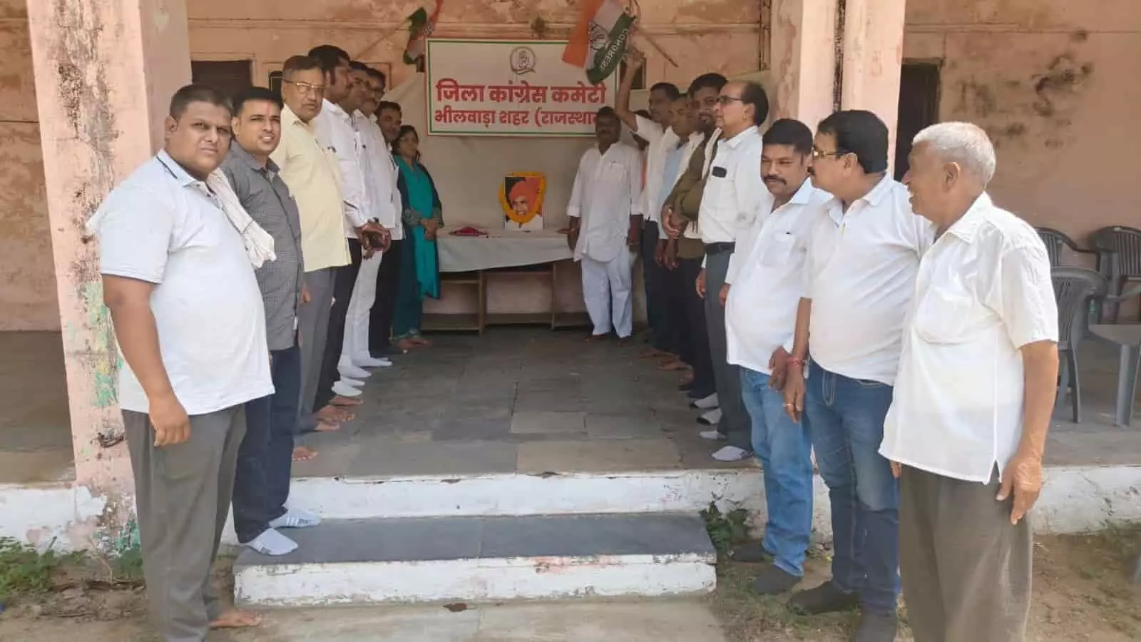 तस्वीर में जिला कांग्रेस कमेटी के कार्यालय के बाहर कुछ लोग कतार में खड़े होकर श्रद्धांजलि सभा में भाग लेते हुए।