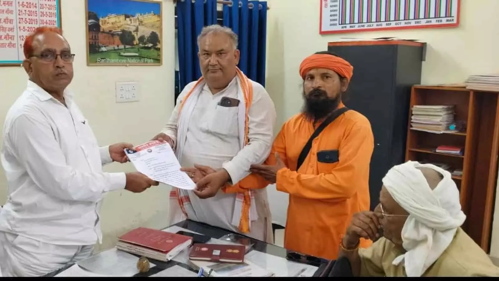 तस्वीर में तीन लोग एक कार्यालय के भीतर टेबल के पास खड़े होकर अधिकारी को सफेद कागज पर लिखा ज्ञापन सौंप रहे हैं। तस्वीर में तीन लोग एक कार्यालय के भीतर टेबल के पास खड़े होकर अधिकारी को सफेद कागज पर लिखा ज्ञापन सौंप रहे हैं।