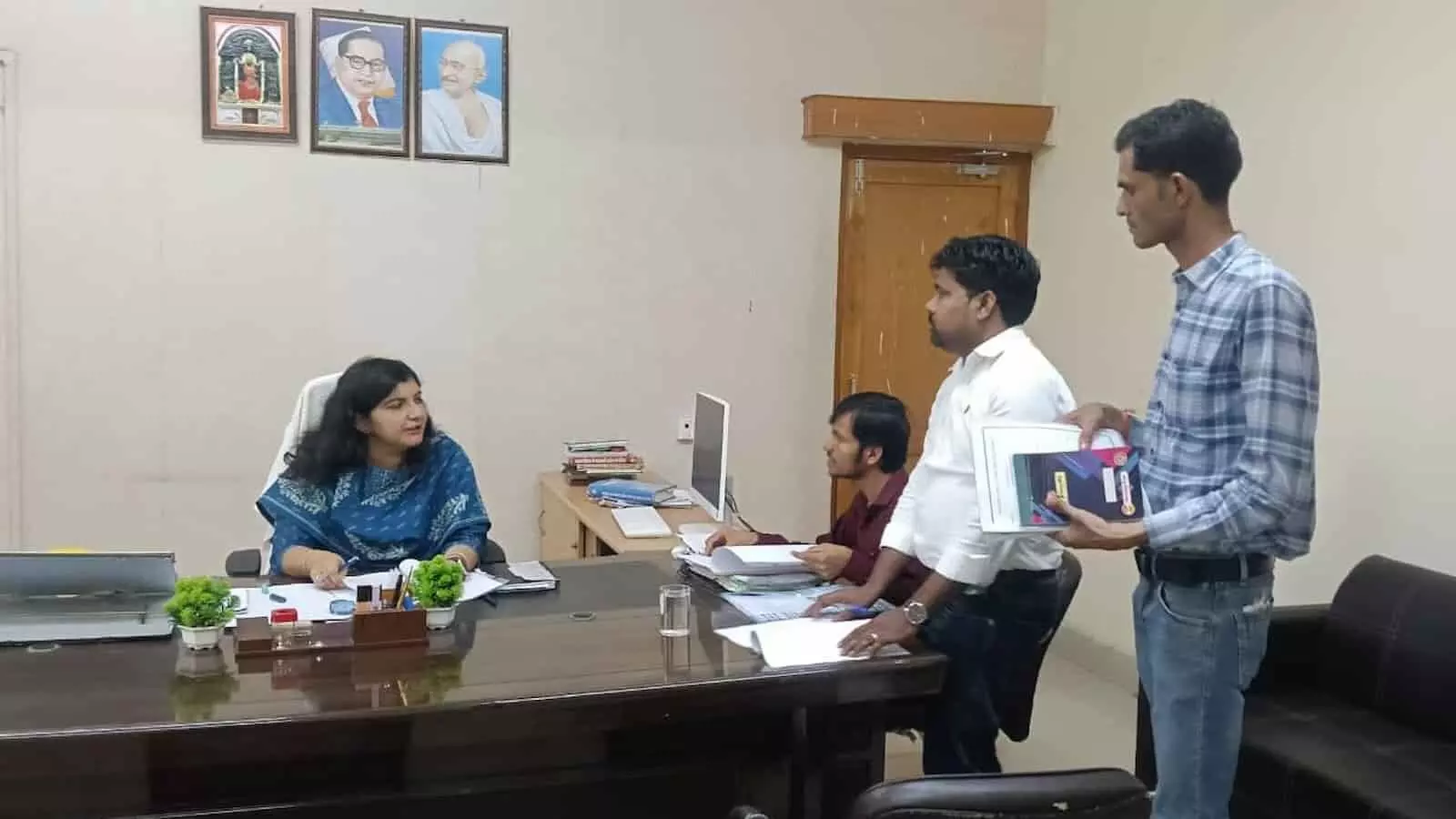 तस्वीर में एक प्रशासनिक दफ्तर के भीतर जिला कलक्टर अपने कक्ष में बैठ कर अन्य अधिकारियों और कर्मचारियों के साथ विभागीय कार्यों व लंबित फाइलों पर चर्चा करती हुई दिख रही हैं। तस्वीर में एक प्रशासनिक दफ्तर के भीतर जिला कलक्टर अपने कक्ष में बैठ कर अन्य अधिकारियों और कर्मचारियों के साथ विभागीय कार्यों व लंबित फाइलों पर चर्चा करती हुई दिख रही हैं।