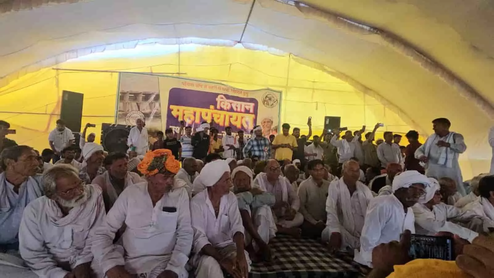 तस्वीर में पीले और सफेद टेंट के नीचे बड़ी संख्या में एकत्र हुए ग्रामीण और मंच के पास खड़े लोग पांचना बांध से पानी छोड़ने के लिए चल रहे अनिश्चितकालीन किसान आंदोलन के संदर्भ में दिख रहे हैं। तस्वीर में पीले और सफेद टेंट के नीचे बड़ी संख्या में एकत्र हुए ग्रामीण और मंच के पास खड़े लोग पांचना बांध से पानी छोड़ने के लिए चल रहे अनिश्चितकालीन किसान आंदोलन के संदर्भ में दिख रहे हैं।