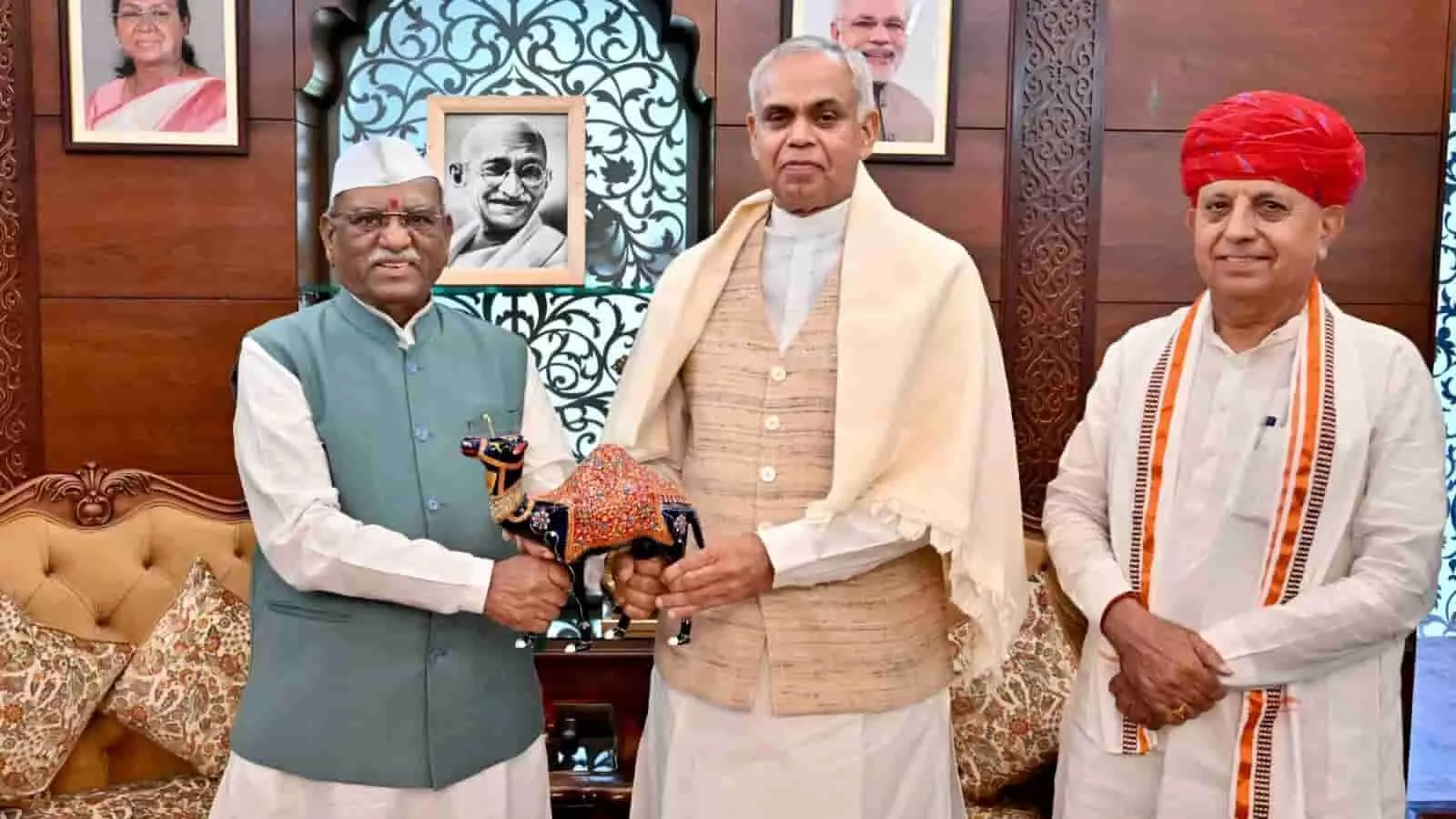 तस्वीर में राजस्थान के राज्यपाल हरिभाऊ बागड़े दो अन्य अतिथियों के साथ खड़े हैं, जिनमें से एक उन्हें सजावटी ऊंट की सुंदर कलाकृति भेंट कर रहा है। तस्वीर में राजस्थान के राज्यपाल हरिभाऊ बागड़े दो अन्य अतिथियों के साथ खड़े हैं, जिनमें से एक उन्हें सजावटी ऊंट की सुंदर कलाकृति भेंट कर रहा है।