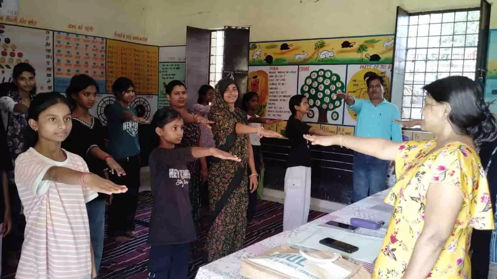 तस्वीर में एक कक्षा के भीतर ब्लैकबोर्ड के सामने कुछ शिक्षक और वक्ता कुर्सियों पर बैठे हैं तथा सामने फर्श पर कई छात्राएं ध्यानपूर्वक उनकी बातें सुन रही हैं। तस्वीर में एक कक्षा के भीतर ब्लैकबोर्ड के सामने कुछ शिक्षक और वक्ता कुर्सियों पर बैठे हैं तथा सामने फर्श पर कई छात्राएं ध्यानपूर्वक उनकी बातें सुन रही हैं।