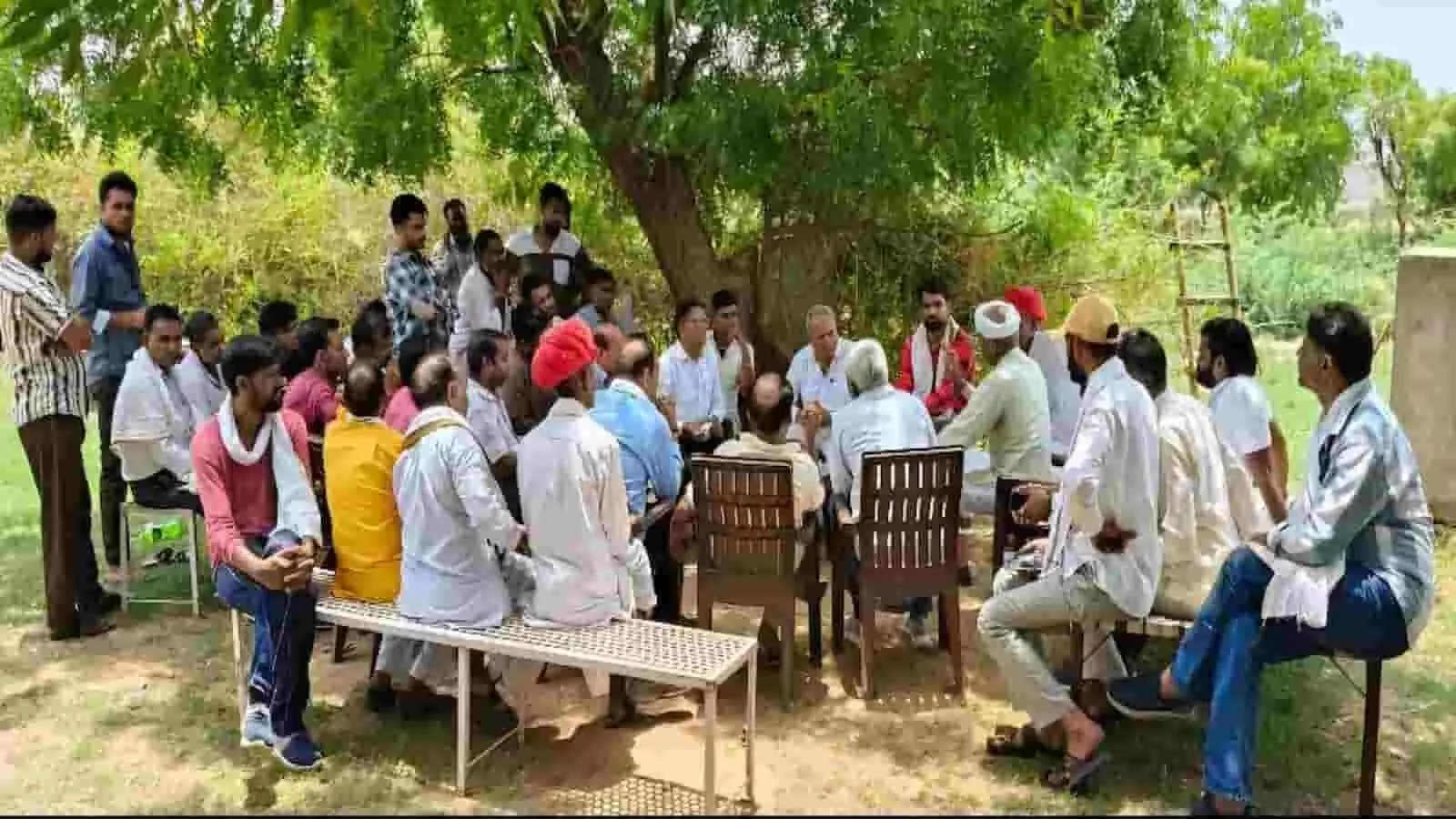 तस्वीर में एक बड़े और घने पेड़ के नीचे ग्रामीण परिवेश में कई लोग कुर्सियों तथा बेंचों पर एक घेरा बनाकर बैठे हैं और आपस में गंभीर चर्चा कर रहे हैं。 तस्वीर में एक बड़े और घने पेड़ के नीचे ग्रामीण परिवेश में कई लोग कुर्सियों तथा बेंचों पर एक घेरा बनाकर बैठे हैं और आपस में गंभीर चर्चा कर रहे हैं。