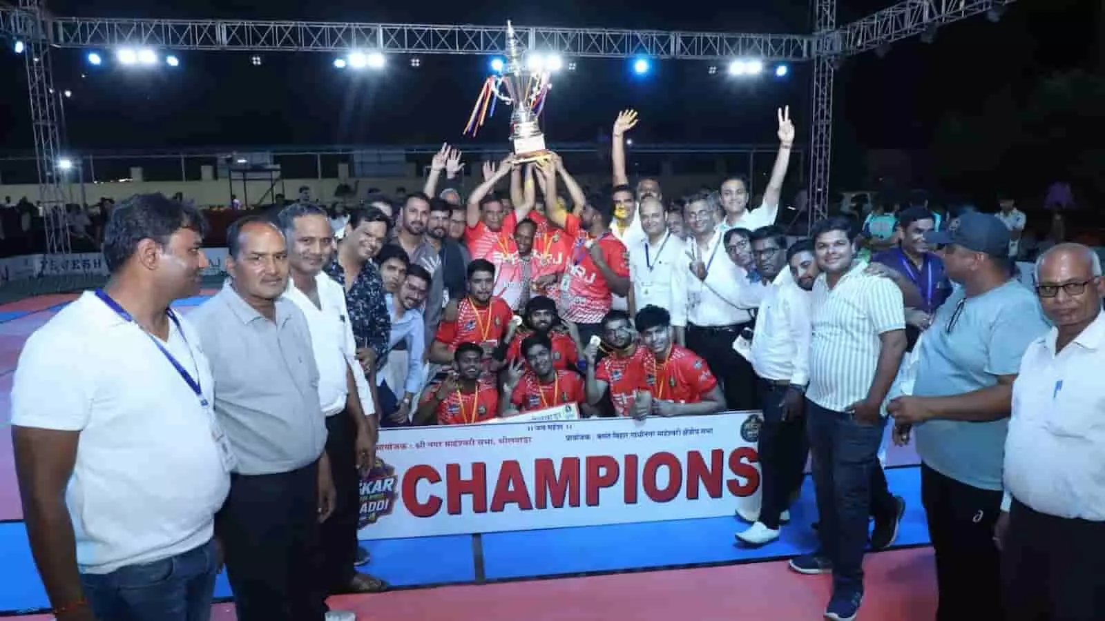 भीलवाड़ा में महेश प्रो कबड्डी प्रतियोगिता जीतने के बाद ट्रॉफी के साथ जश्न मनाते भोपालगंज टीम के खिलाड़ी और अतिथि। भीलवाड़ा में महेश प्रो कबड्डी प्रतियोगिता जीतने के बाद ट्रॉफी के साथ जश्न मनाते भोपालगंज टीम के खिलाड़ी और अतिथि।