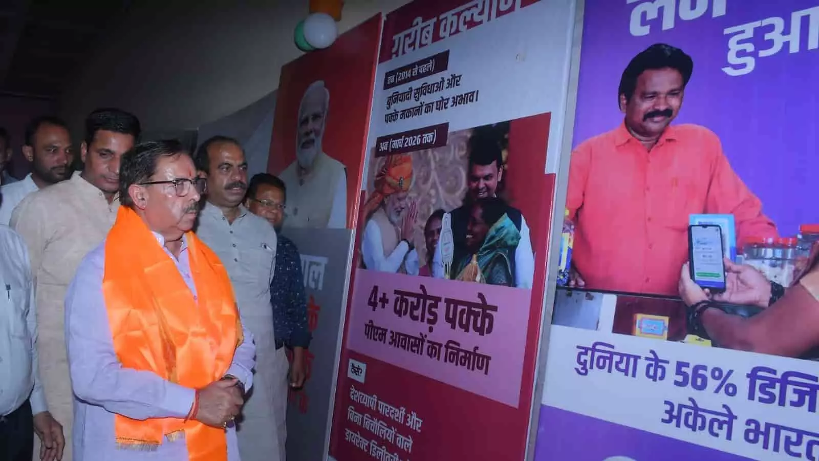 तस्वीर में कुछ नेता और अधिकारी एक सभागार के भीतर दीवारों पर लगी सरकारी योजनाओं और उपलब्धियों की विकासात्मक प्रदर्शनियों को देखते हुए खड़े नजर आ रहे हैं। तस्वीर में कुछ नेता और अधिकारी एक सभागार के भीतर दीवारों पर लगी सरकारी योजनाओं और उपलब्धियों की विकासात्मक प्रदर्शनियों को देखते हुए खड़े नजर आ रहे हैं।