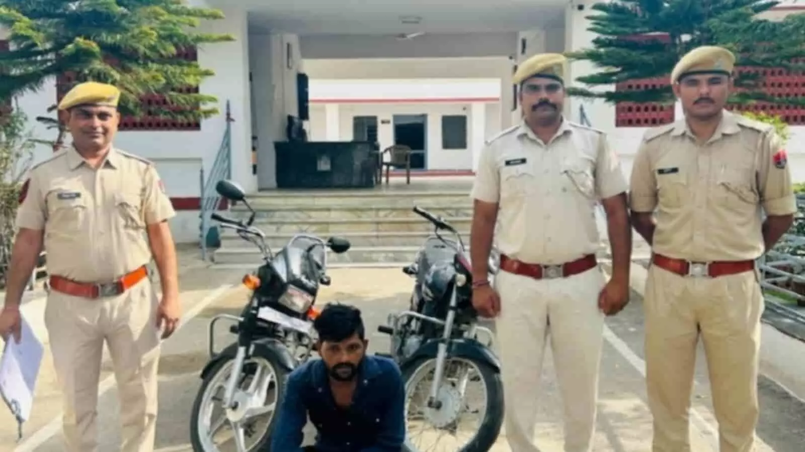 तस्वीर में खाकी वर्दी पहने तीन पुलिस जवानों के बीच दो मोटरसाइकिलें खड़ी हैं और उनके आगे एक युवक जमीन पर बैठा नजर आ रहा है। तस्वीर में खाकी वर्दी पहने तीन पुलिस जवानों के बीच दो मोटरसाइकिलें खड़ी हैं और उनके आगे एक युवक जमीन पर बैठा नजर आ रहा है।