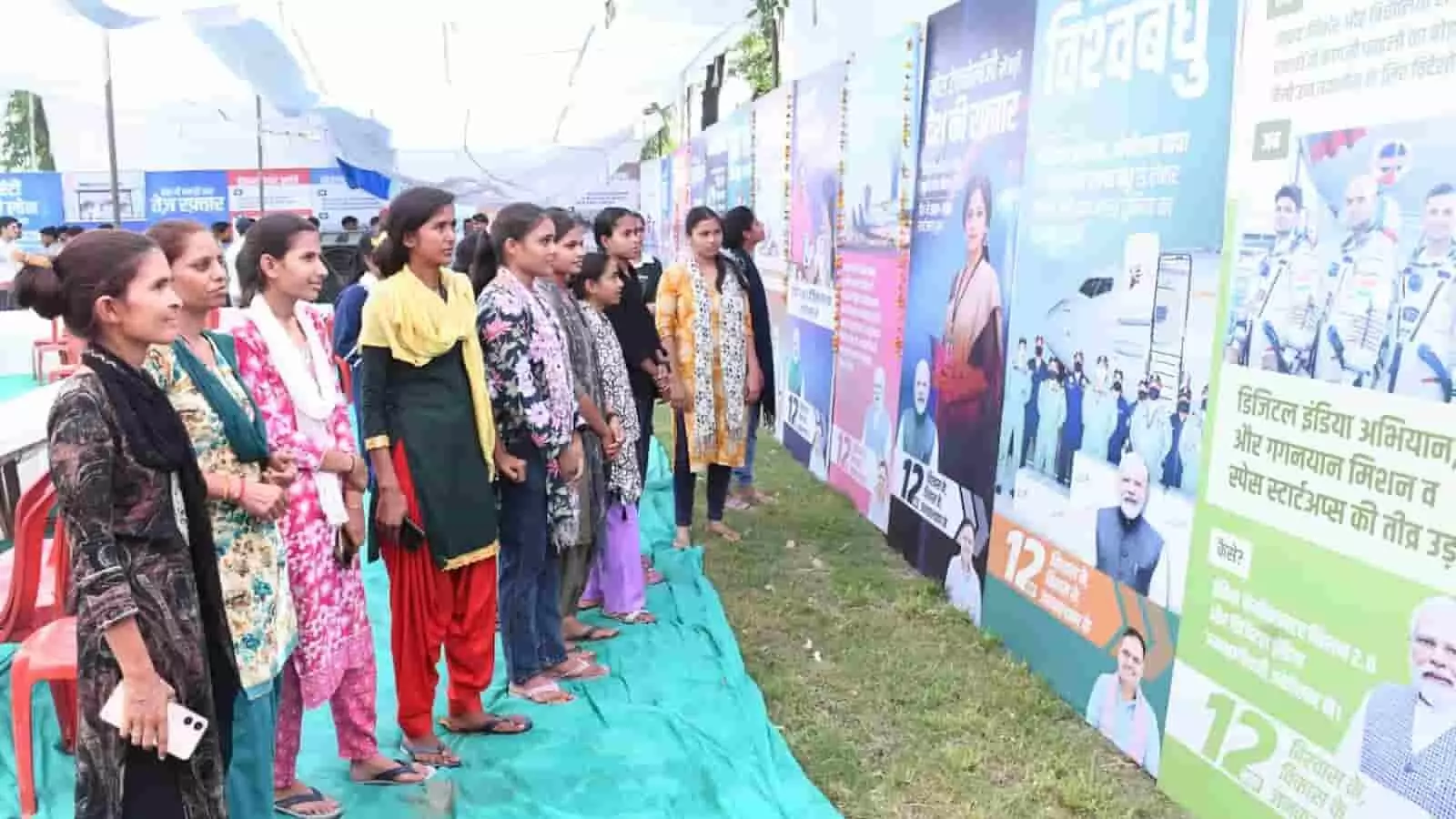 तस्वीर में कई युवतियां और छात्राएं कतार में खड़ी होकर मैदान में लगाए गए बड़े-बड़े सरकारी योजनाओं और उपलब्धियों के होर्डिंग्स (फ्लेक्स) को ध्यान से देख रही हैं। तस्वीर में कई युवतियां और छात्राएं कतार में खड़ी होकर मैदान में लगाए गए बड़े-बड़े सरकारी योजनाओं और उपलब्धियों के होर्डिंग्स (फ्लेक्स) को ध्यान से देख रही हैं।