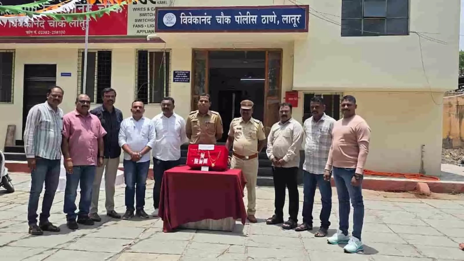 तस्वीर में एक पुलिस थाने के भवन के बाहर पुलिसकर्मी और अन्य लोग एक मेज पर रखे लाल बॉक्स के पास खड़े दिख रहे हैं। तस्वीर में एक पुलिस थाने के भवन के बाहर पुलिसकर्मी और अन्य लोग एक मेज पर रखे लाल बॉक्स के पास खड़े दिख रहे हैं।