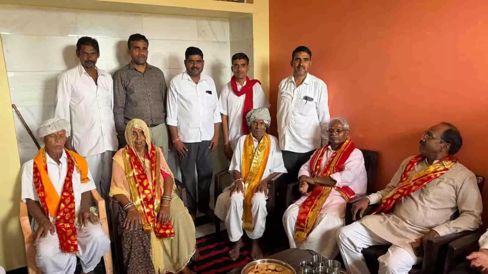 तस्वीर में एक कमरे के भीतर पारंपरिक पगड़ी और लाल-सुनहरे रंग के दुपट्टे पहने कुछ वरिष्ठ नागरिक कुर्सियों पर बैठे तस्वीर में एक कमरे के भीतर पारंपरिक पगड़ी और लाल-सुनहरे रंग के दुपट्टे पहने कुछ वरिष्ठ नागरिक कुर्सियों पर बैठे